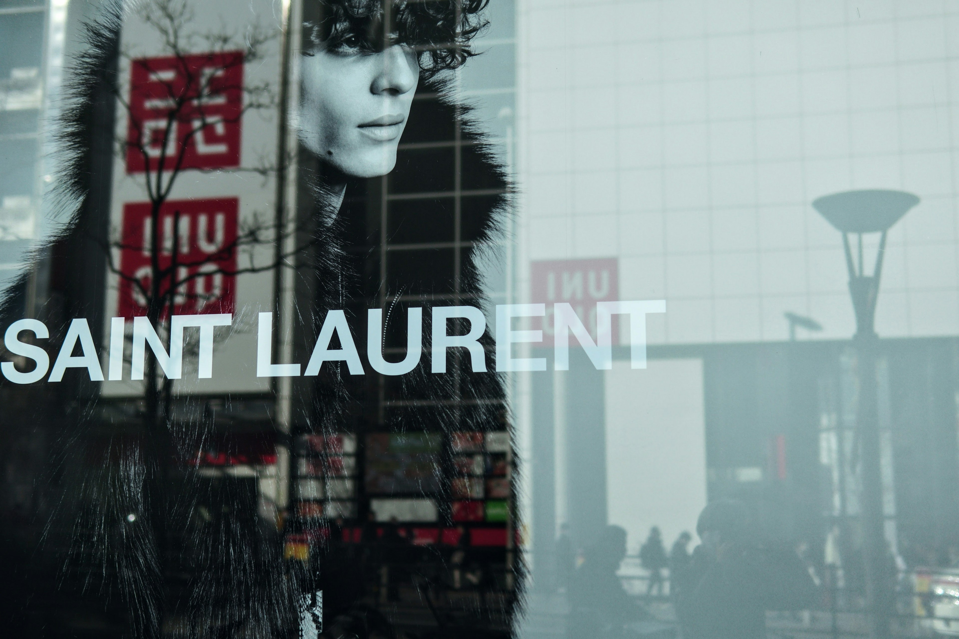 Reflection of a model in Saint Laurent store window with urban background