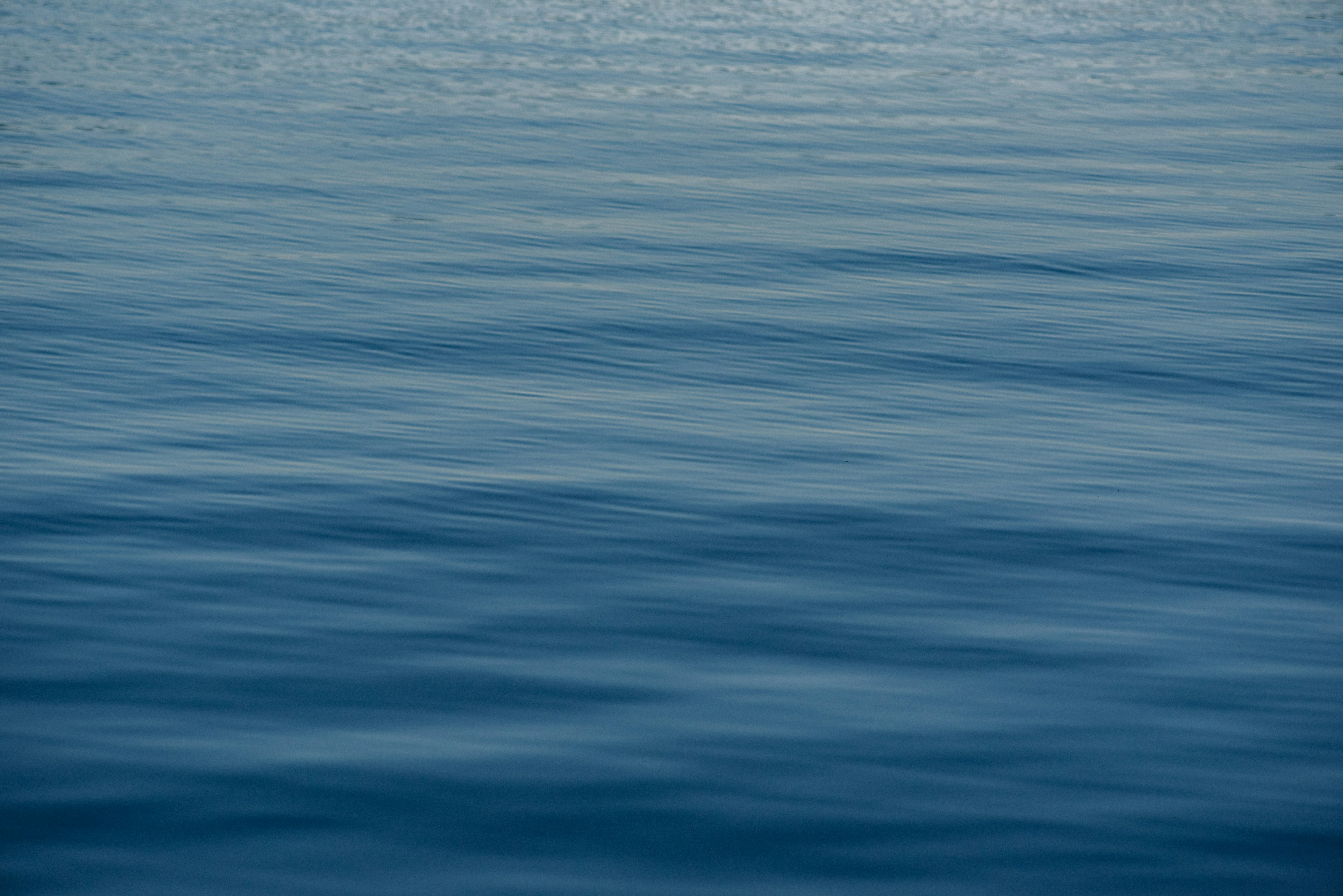 Permukaan laut tenang dengan riak lembut dalam nuansa biru