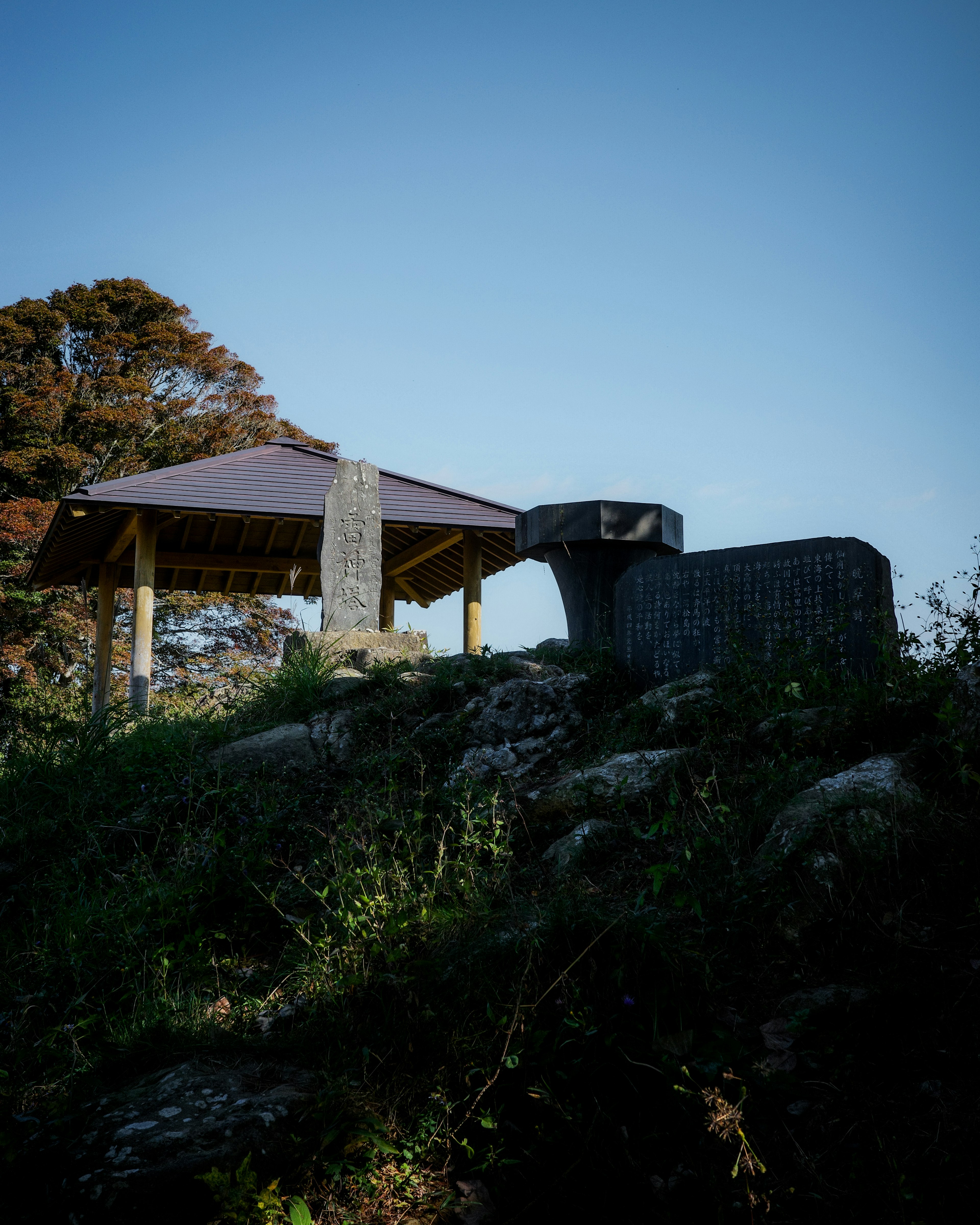 青空の下にある小屋と石の構造物が見える風景