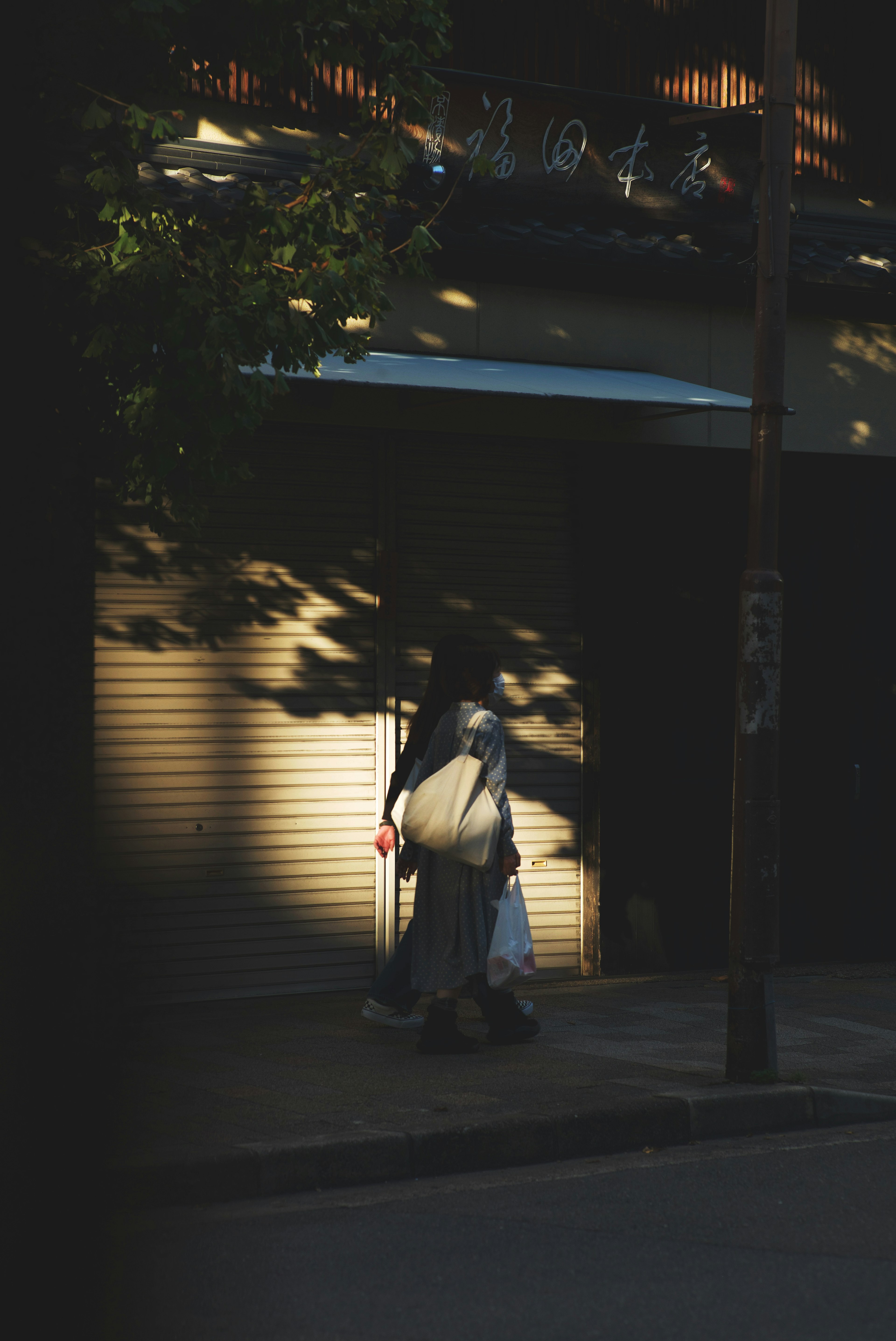 A person walking down a quiet street with shadows