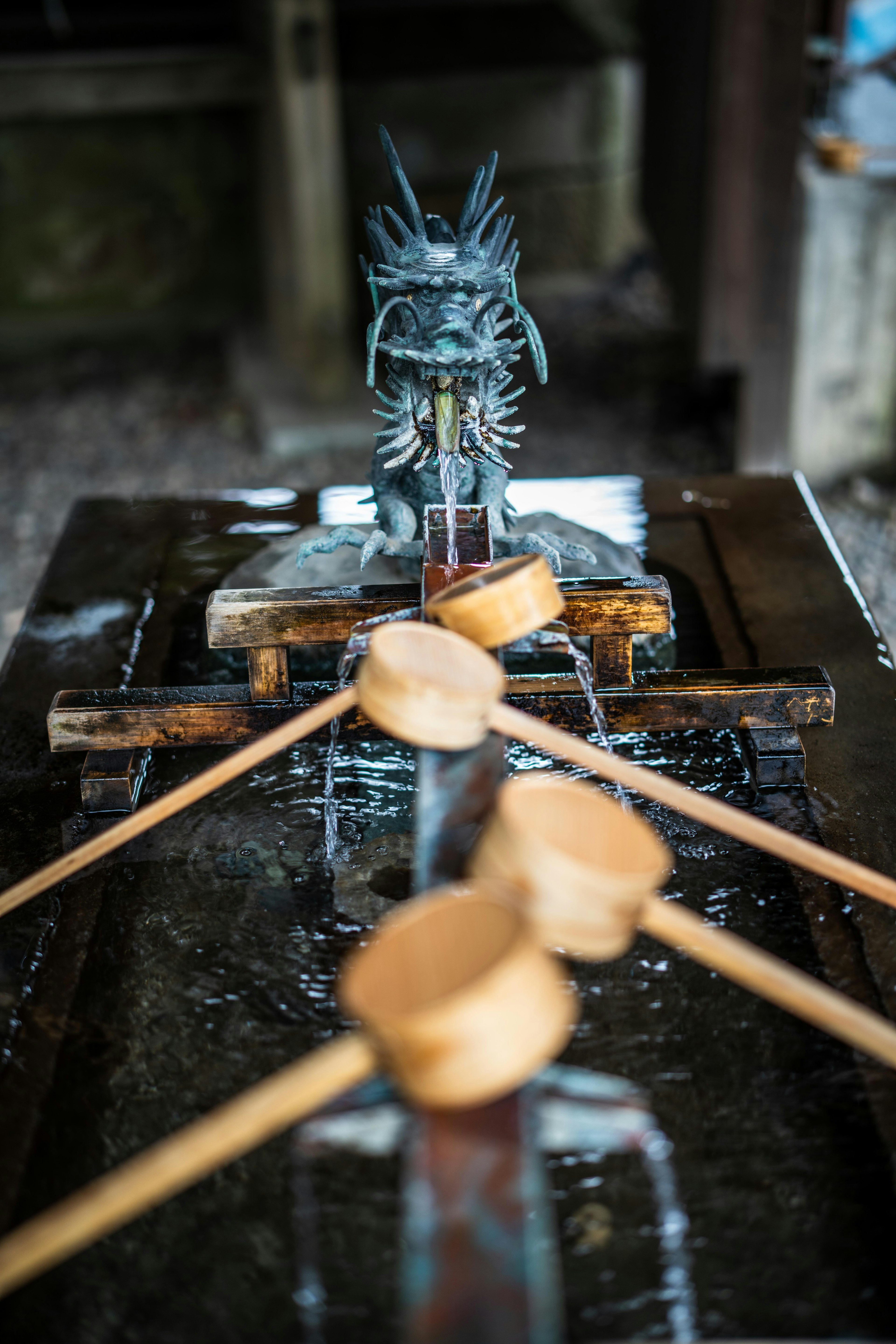 Temizuya eines japanischen Schreins mit Holzlöffeln und einer Drachenskulptur