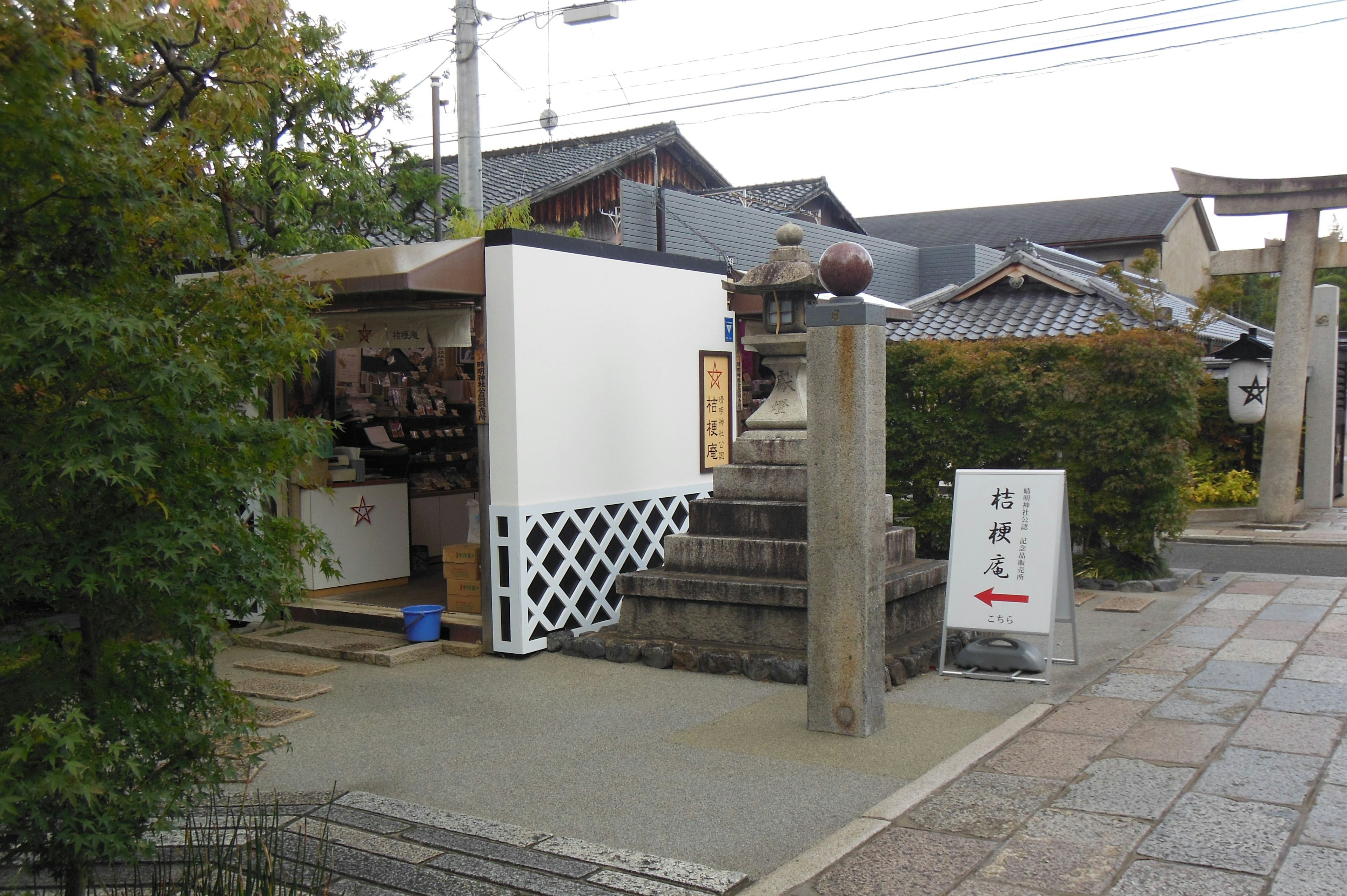 Scene featuring a white building and stone steps close to a shop and shrine