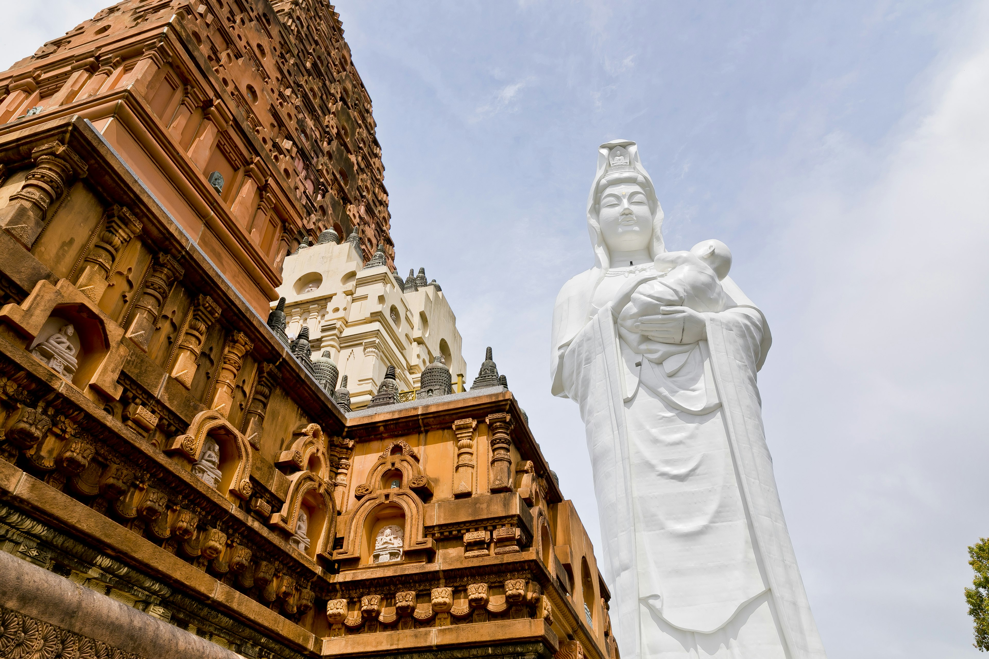 Une statue blanche de Guanyin à côté d'une architecture de temple ancien