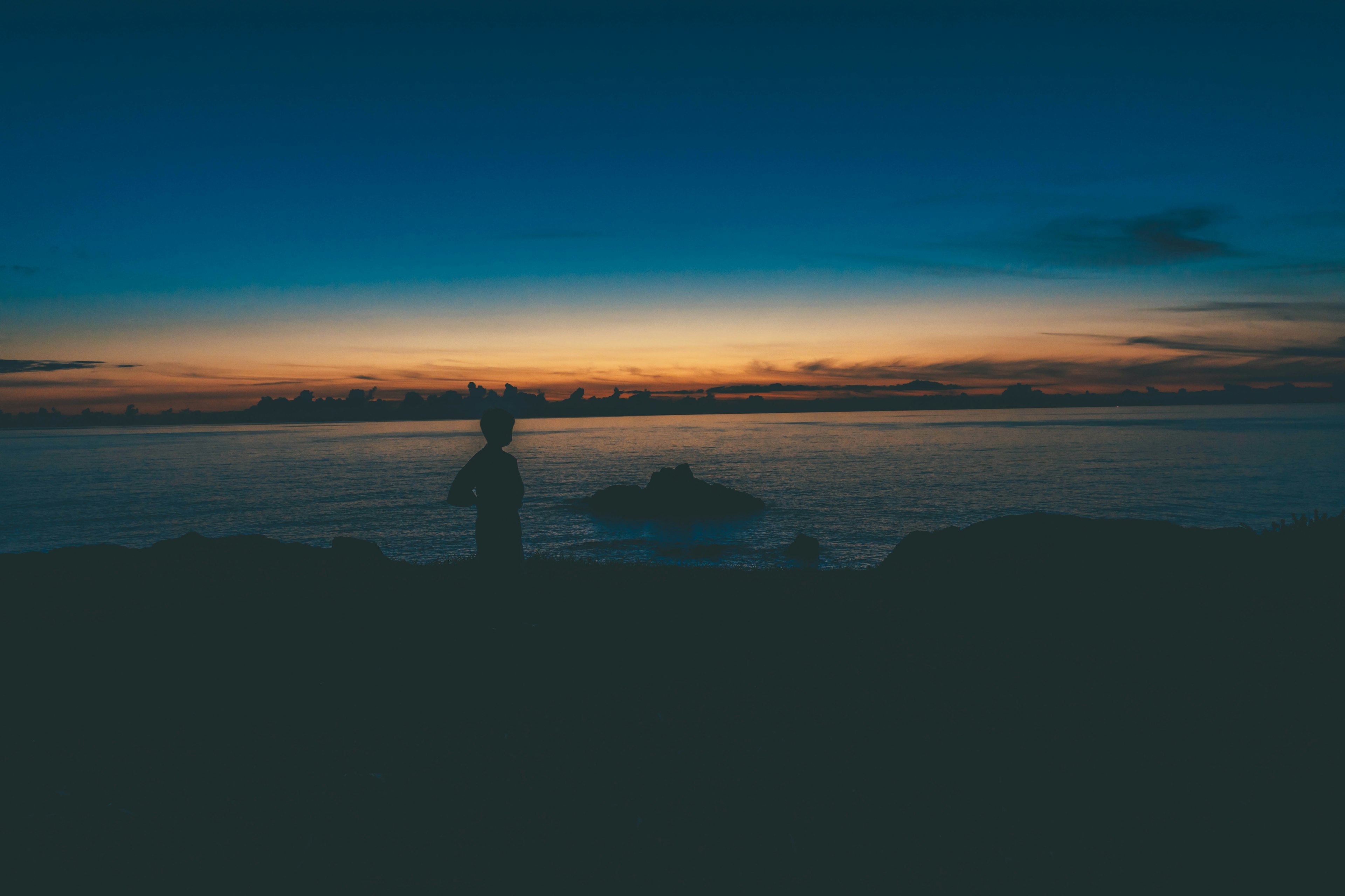 Silueta de una persona contra un tranquilo atardecer y mar