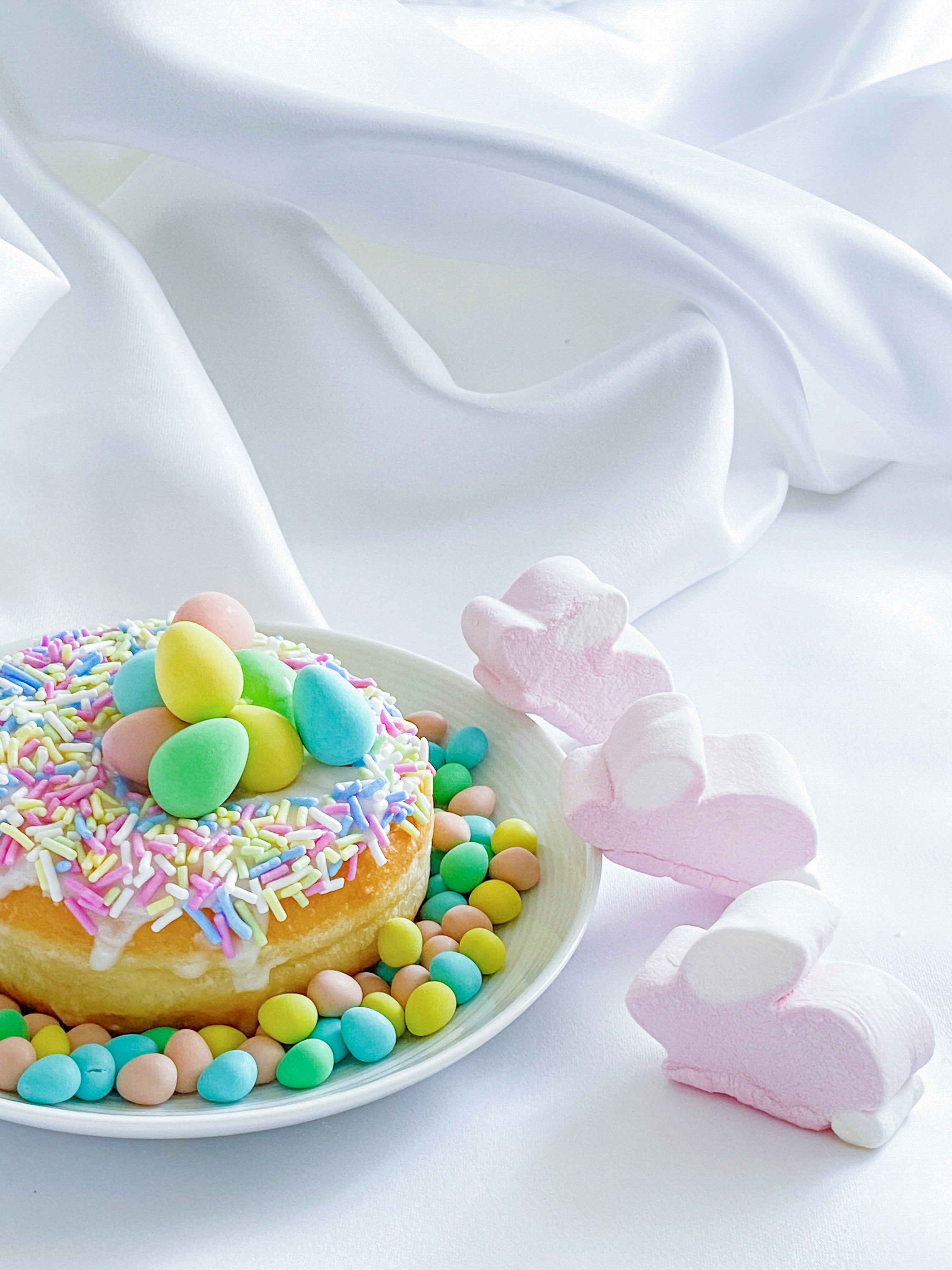 Donat berwarna-warni dengan taburan dan telur coklat di atas piring putih