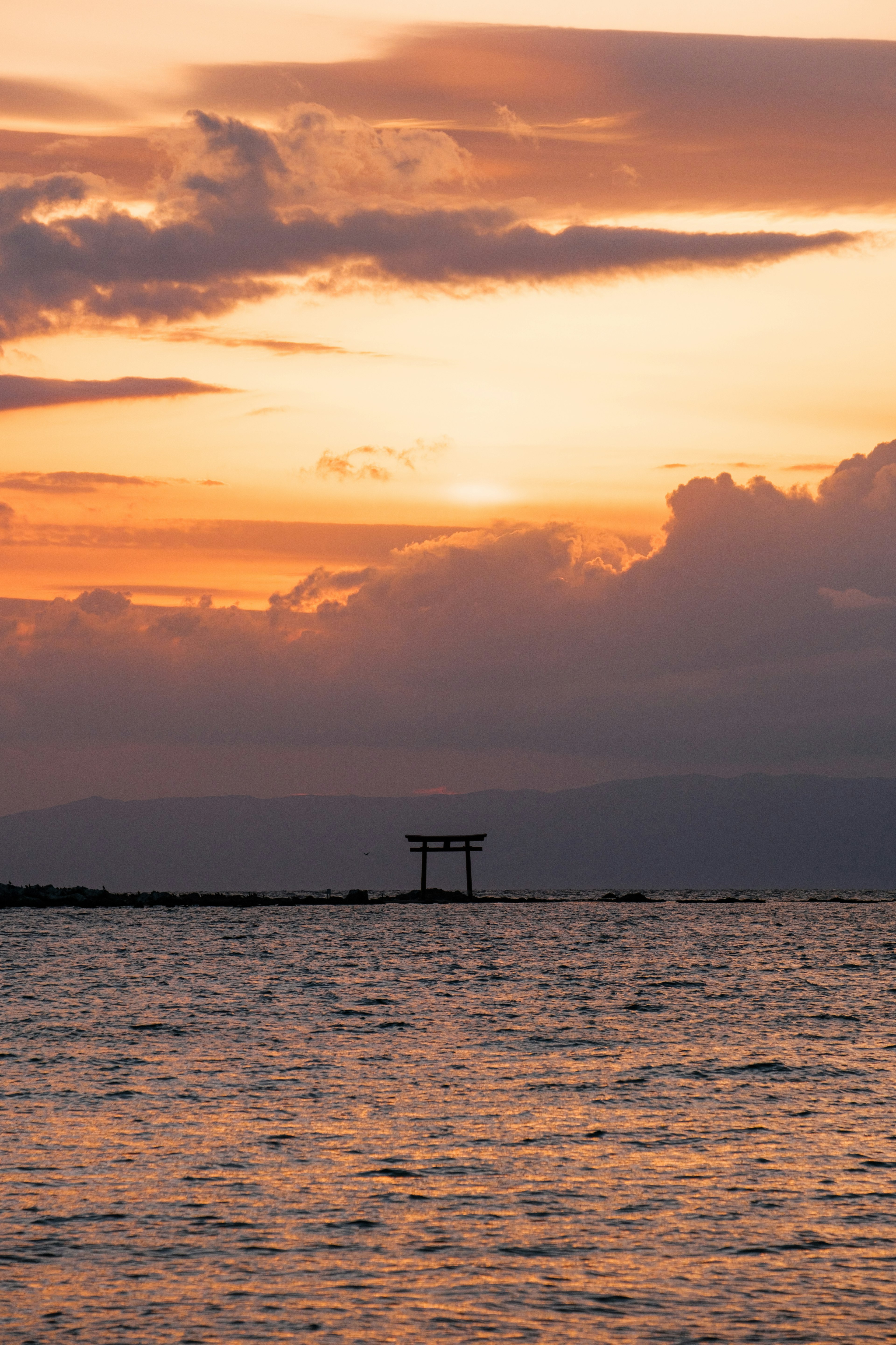 Malerischer Sonnenuntergang über dem Wasser mit Silhouette eines Torii