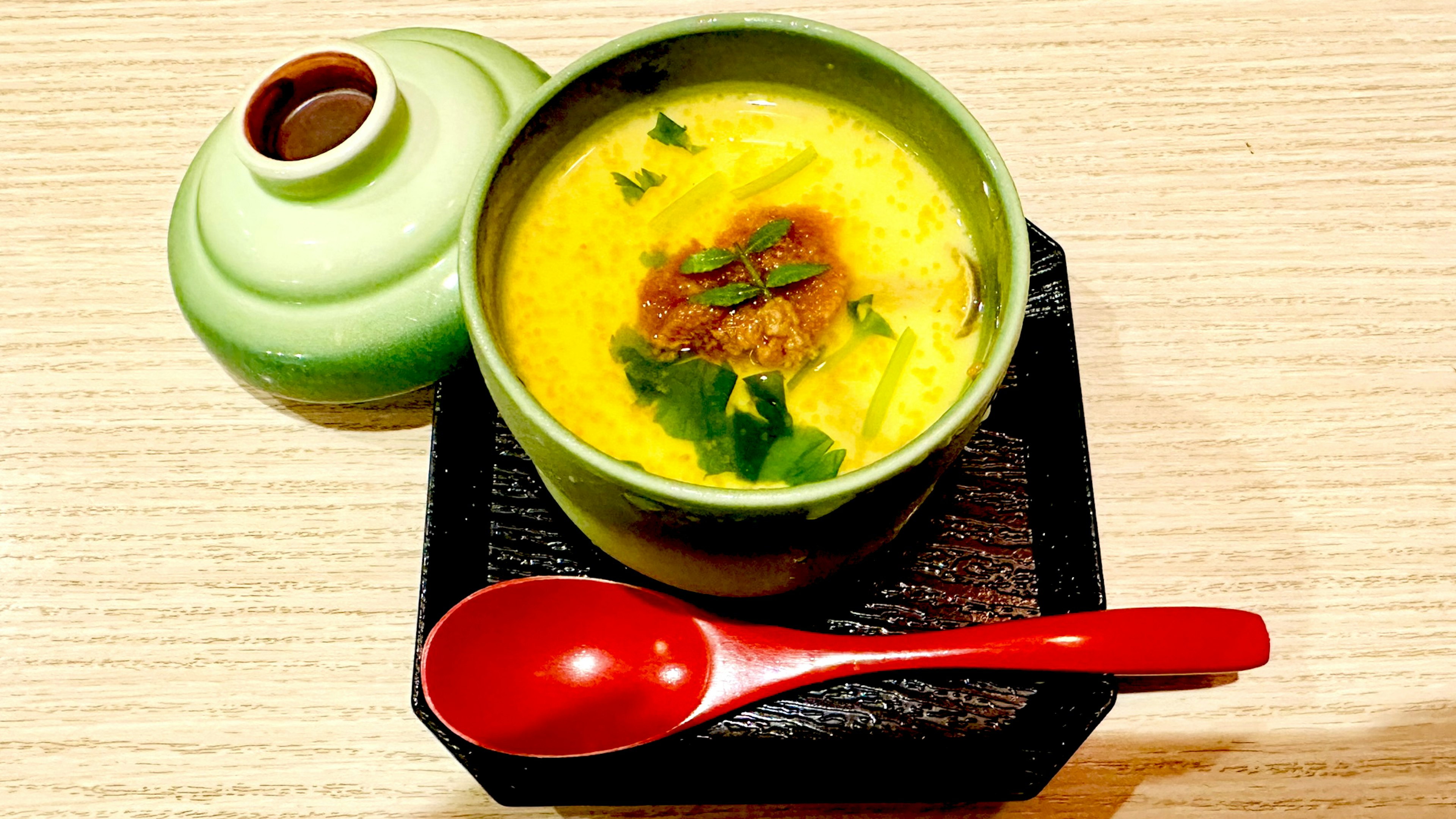 Chawanmushi servido en un tazón verde con cilantro y carne picada