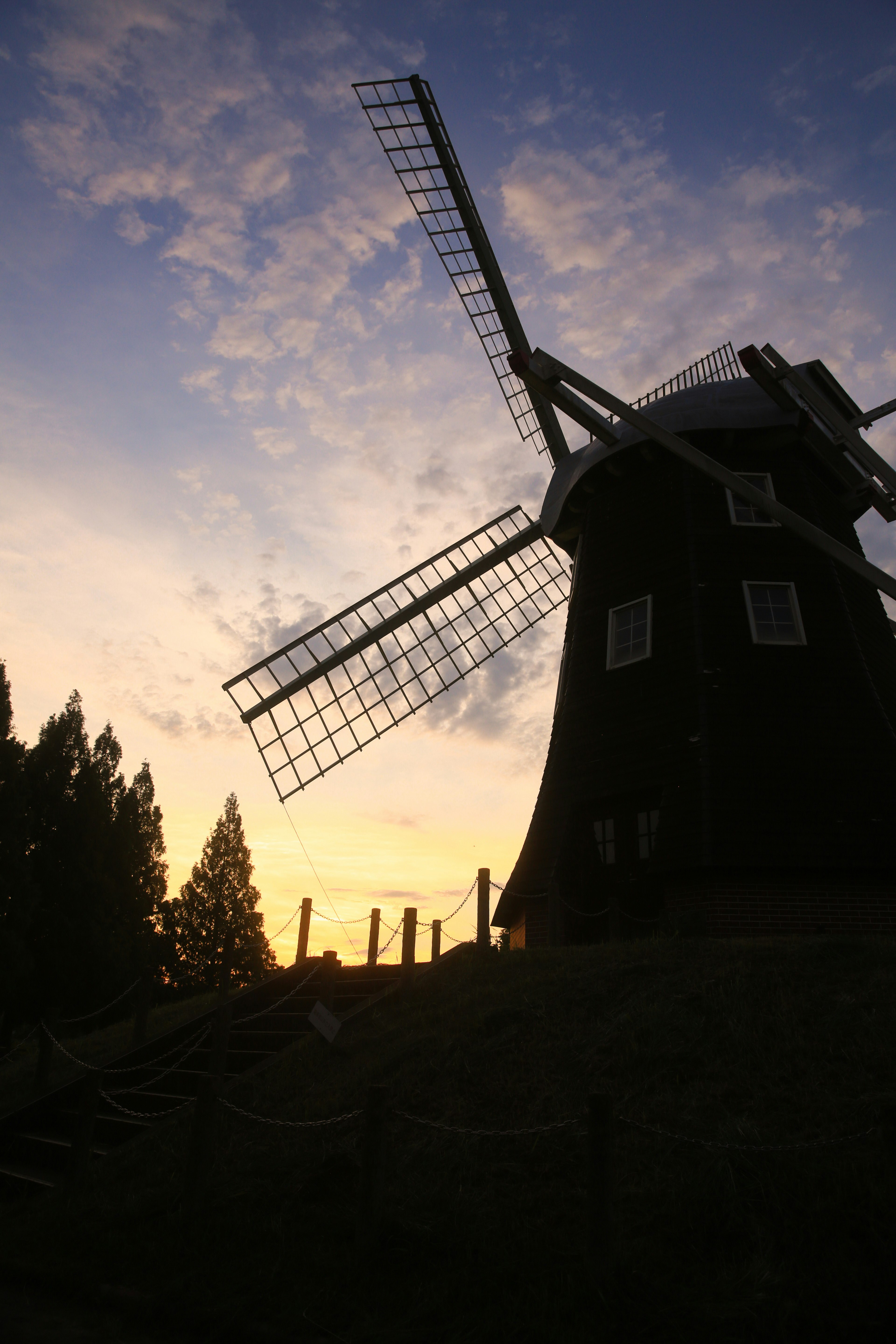 Silhouette of a black windmill against a sunset sky