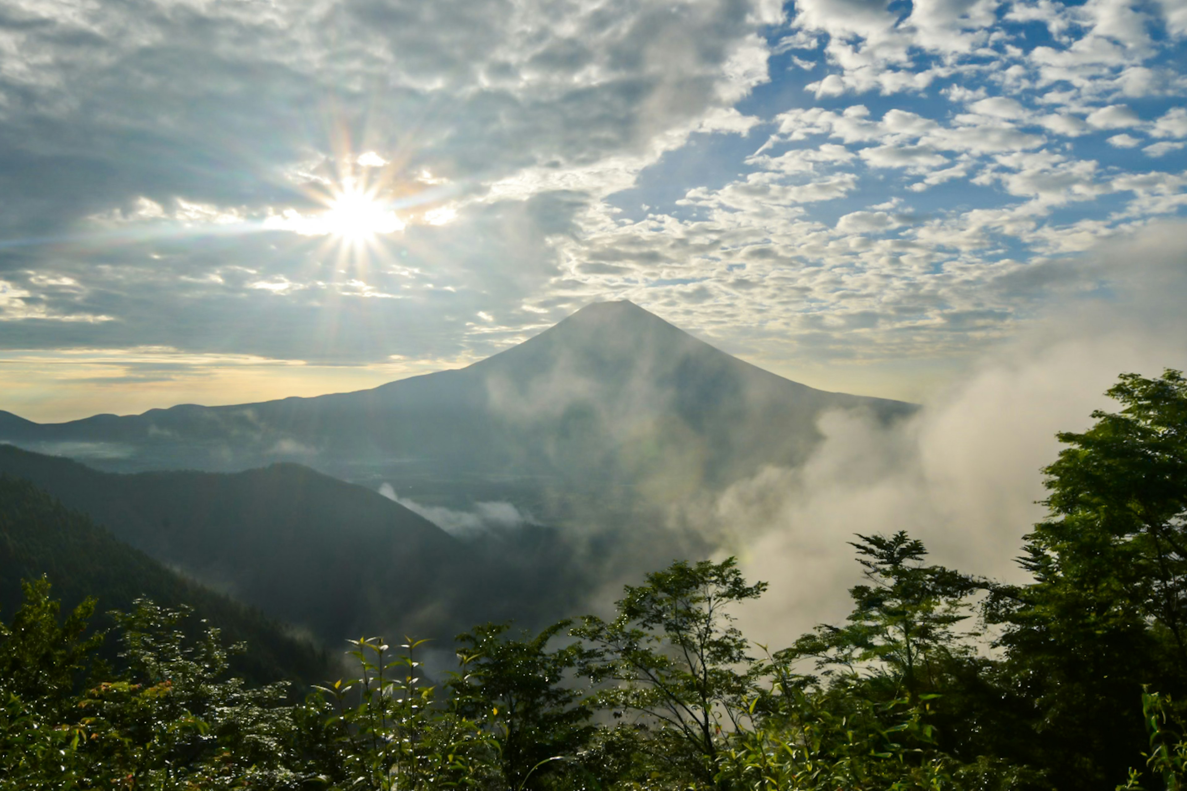 Pemandangan gunung dengan awan dan sinar matahari