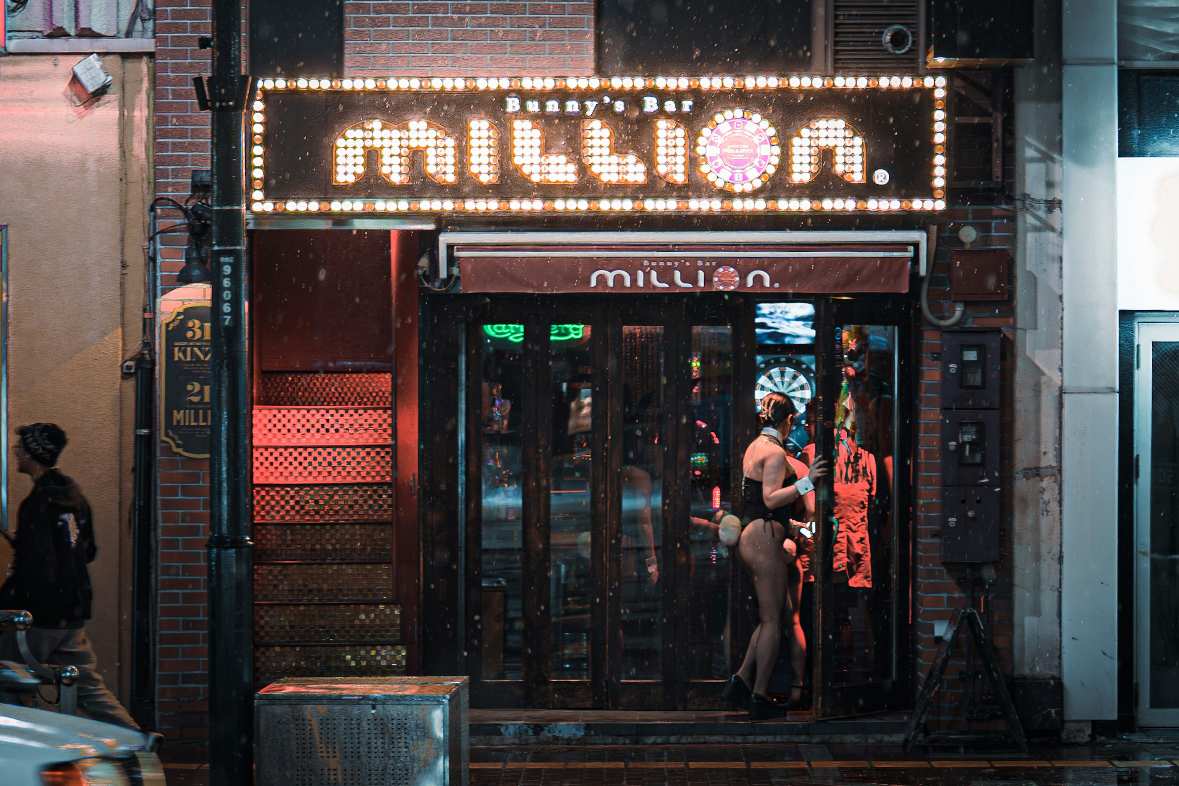 Fachada de un bar con letrero de neón y mujeres afuera