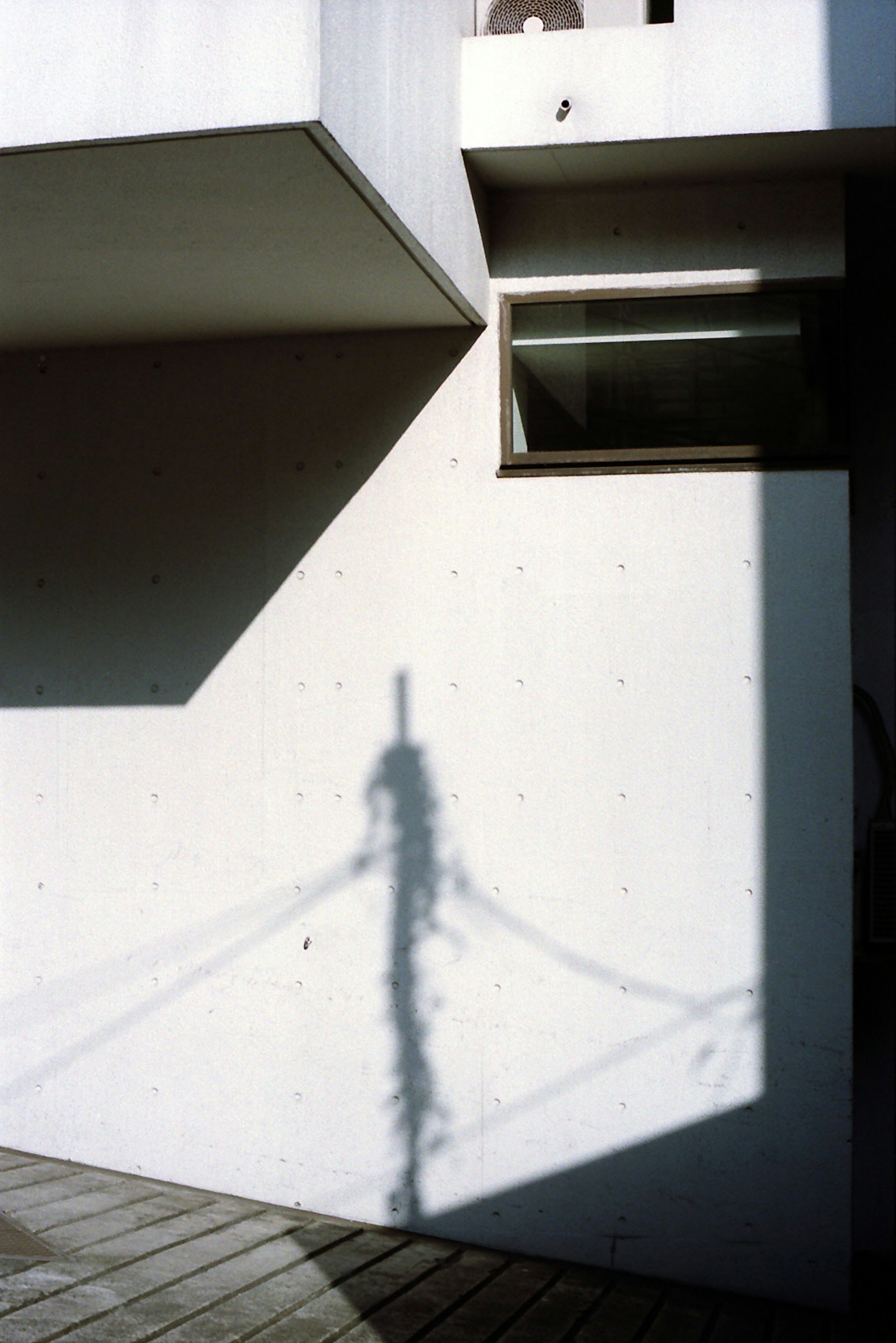 Shadow of a pole on a concrete wall with geometric shapes