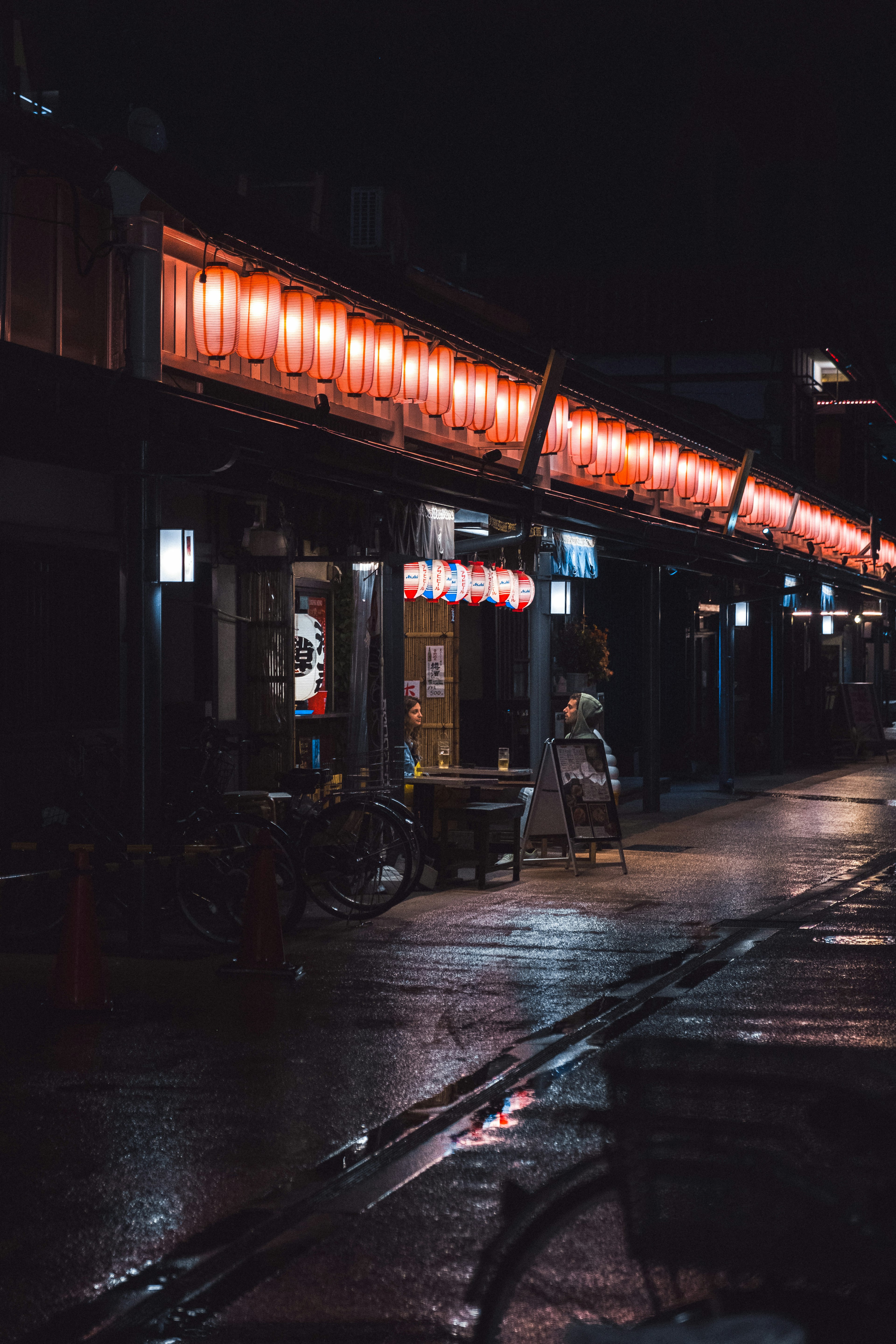 Nighttime street scene with glowing red lanterns in a shopping district