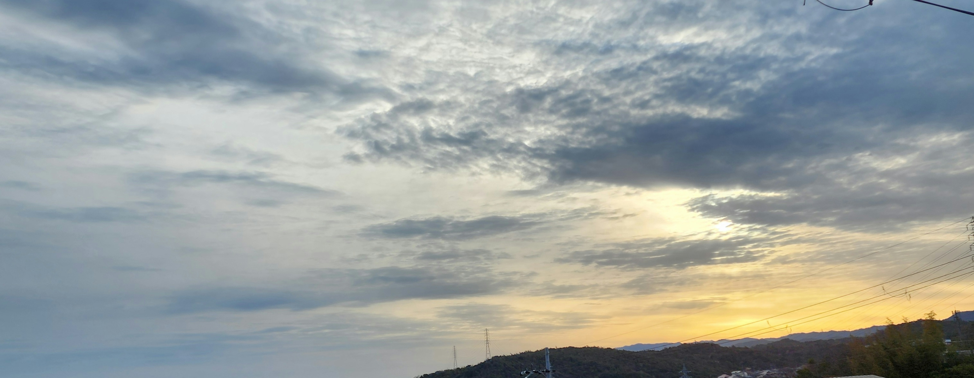 雲に覆われた空と沈む夕日が映る風景