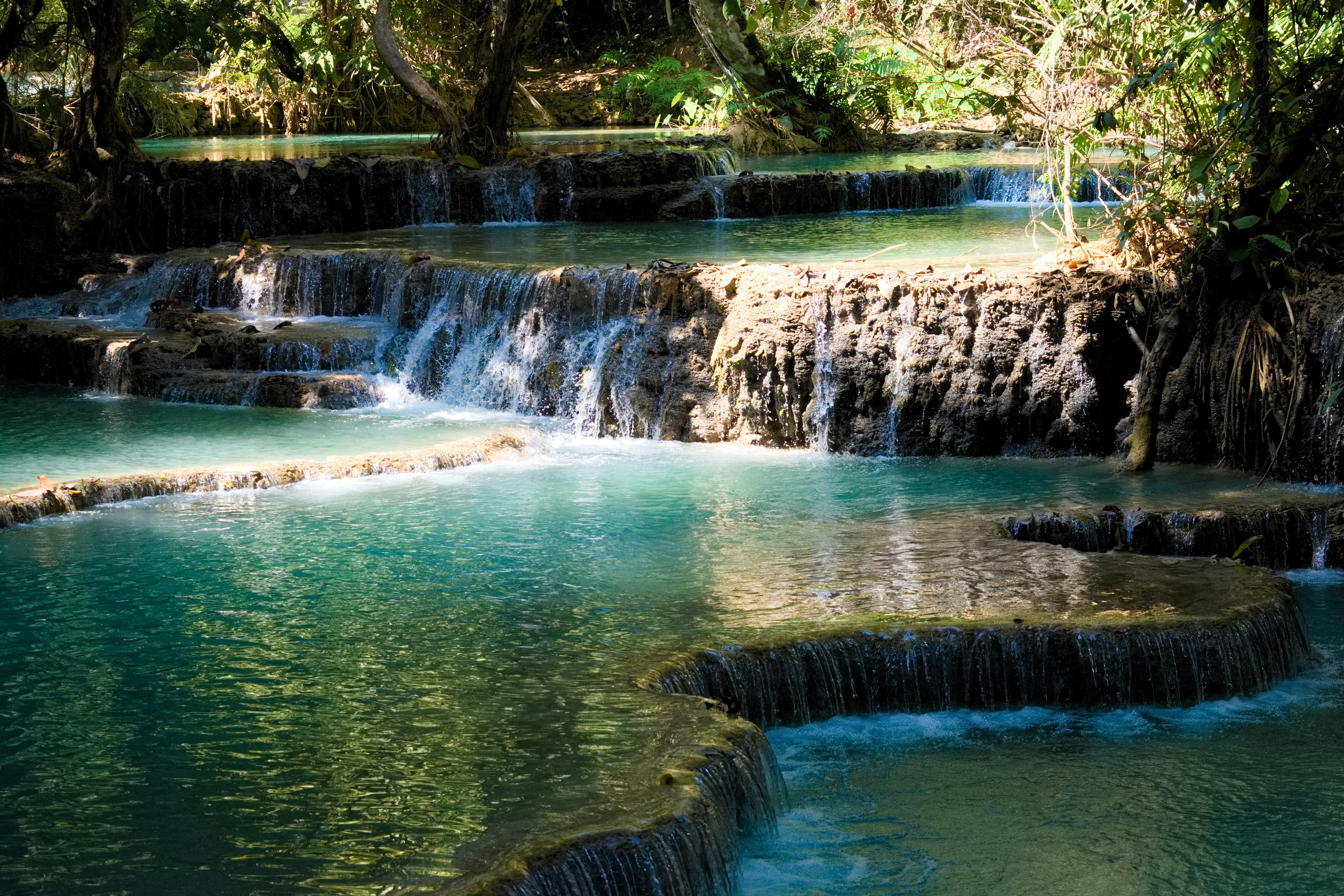 Scenic view of cascading waterfalls and turquoise pools surrounded by lush greenery