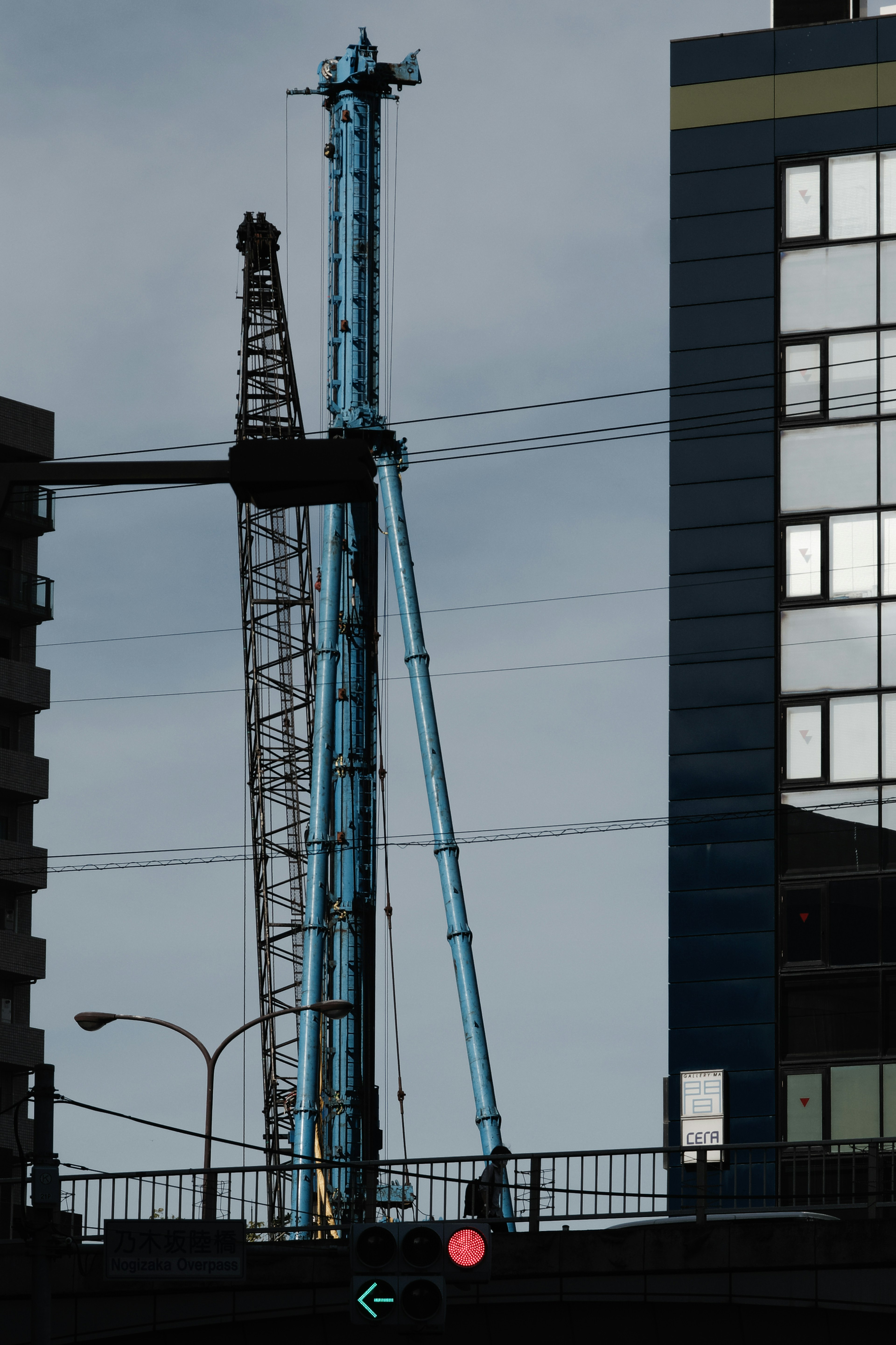 A blue crane standing near a high-rise building with a construction site