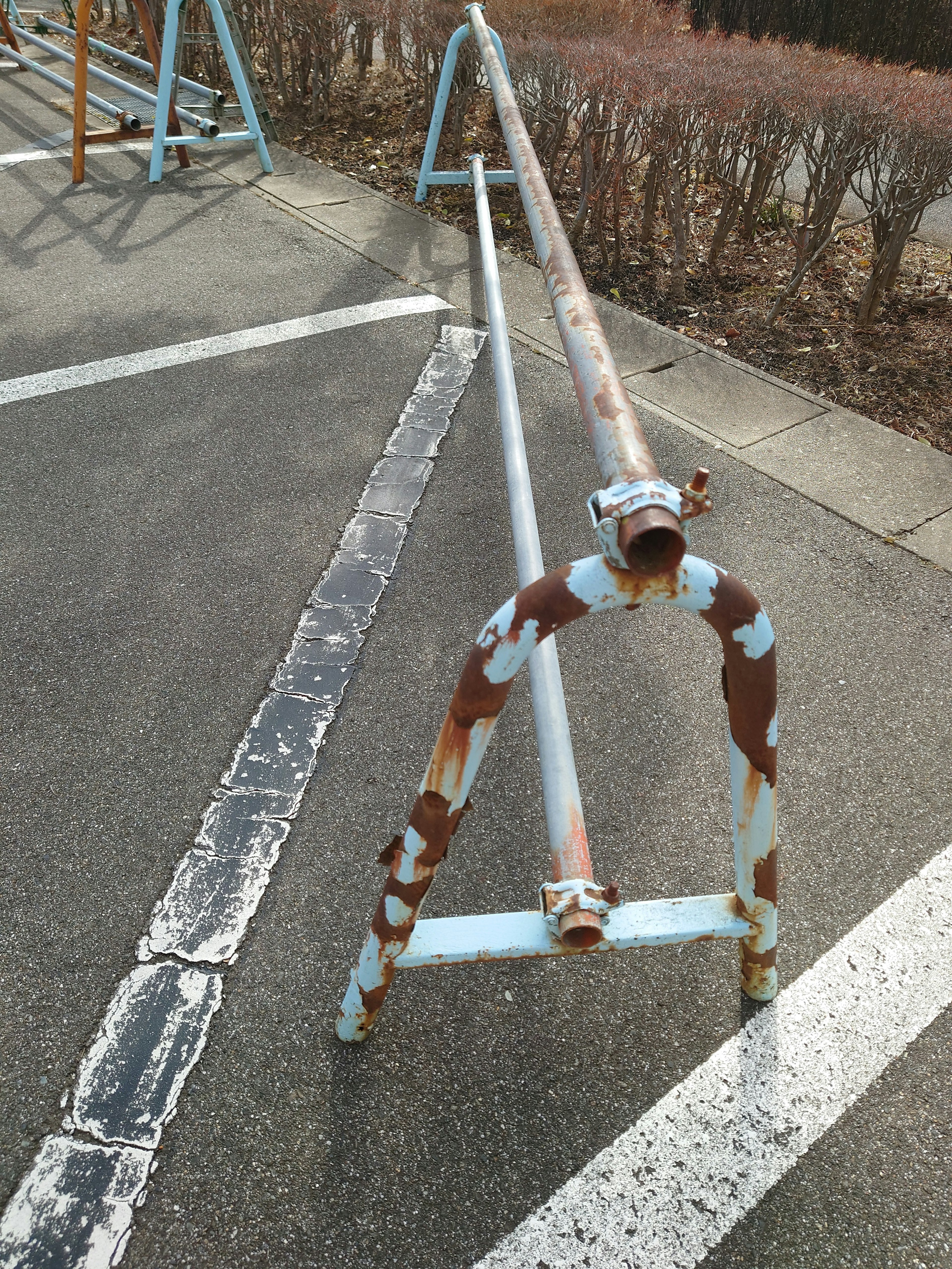 Ancien support à vélos en métal rouillé placé dans un parking