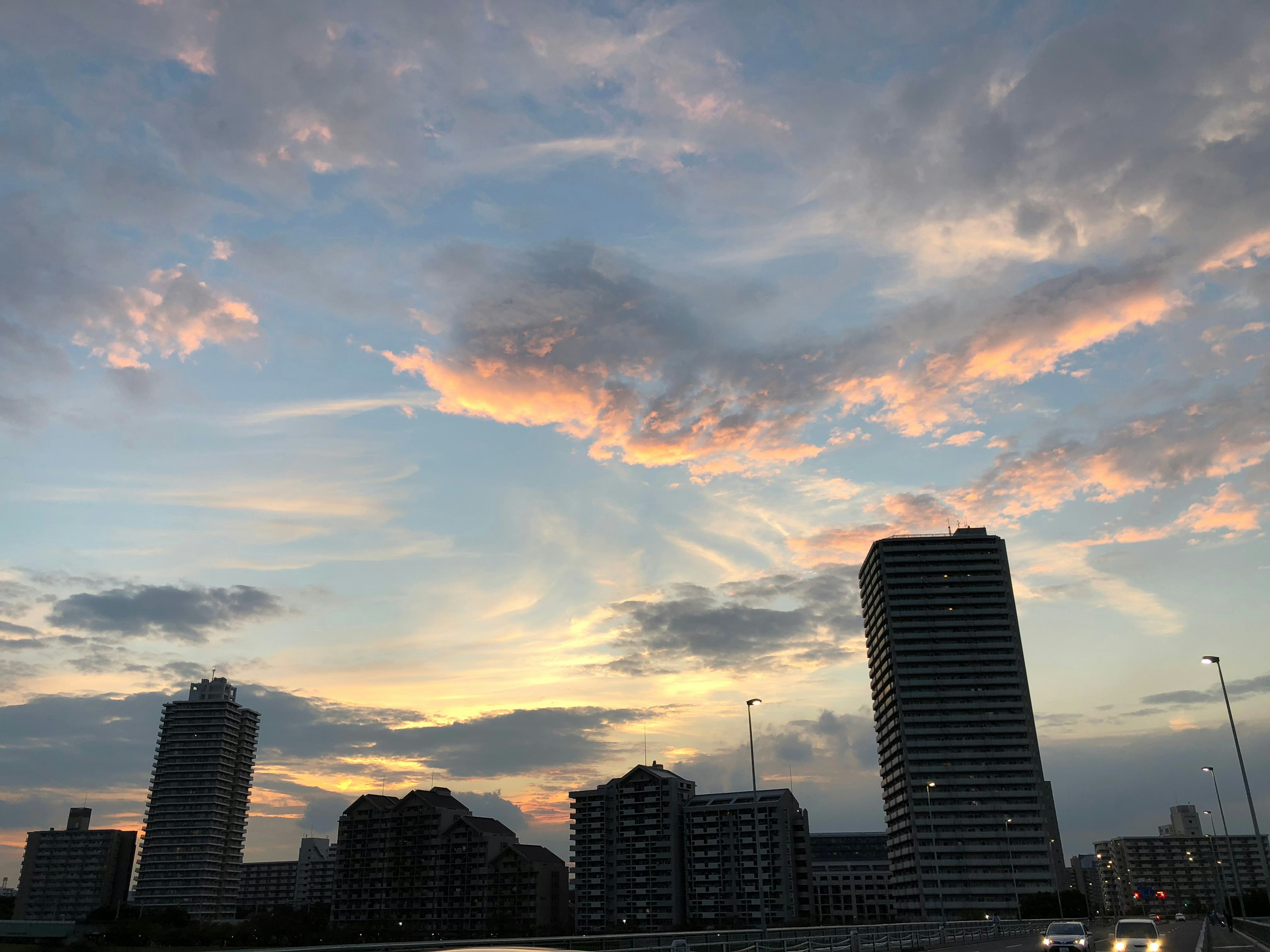 Langit saat matahari terbenam dengan cakrawala kota dan awan