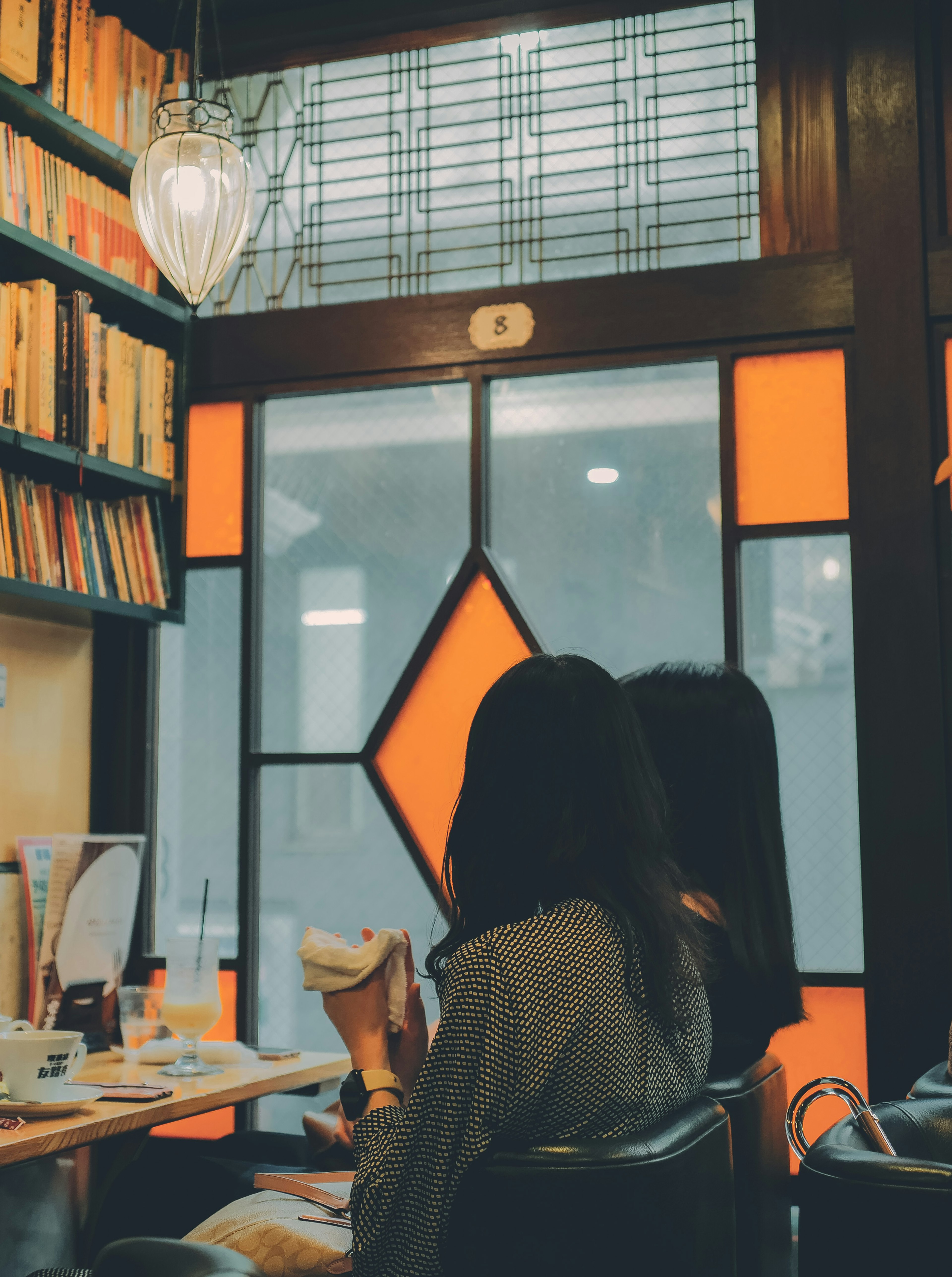 Interior de un café con dos mujeres sentadas y un diseño de ventana naranja