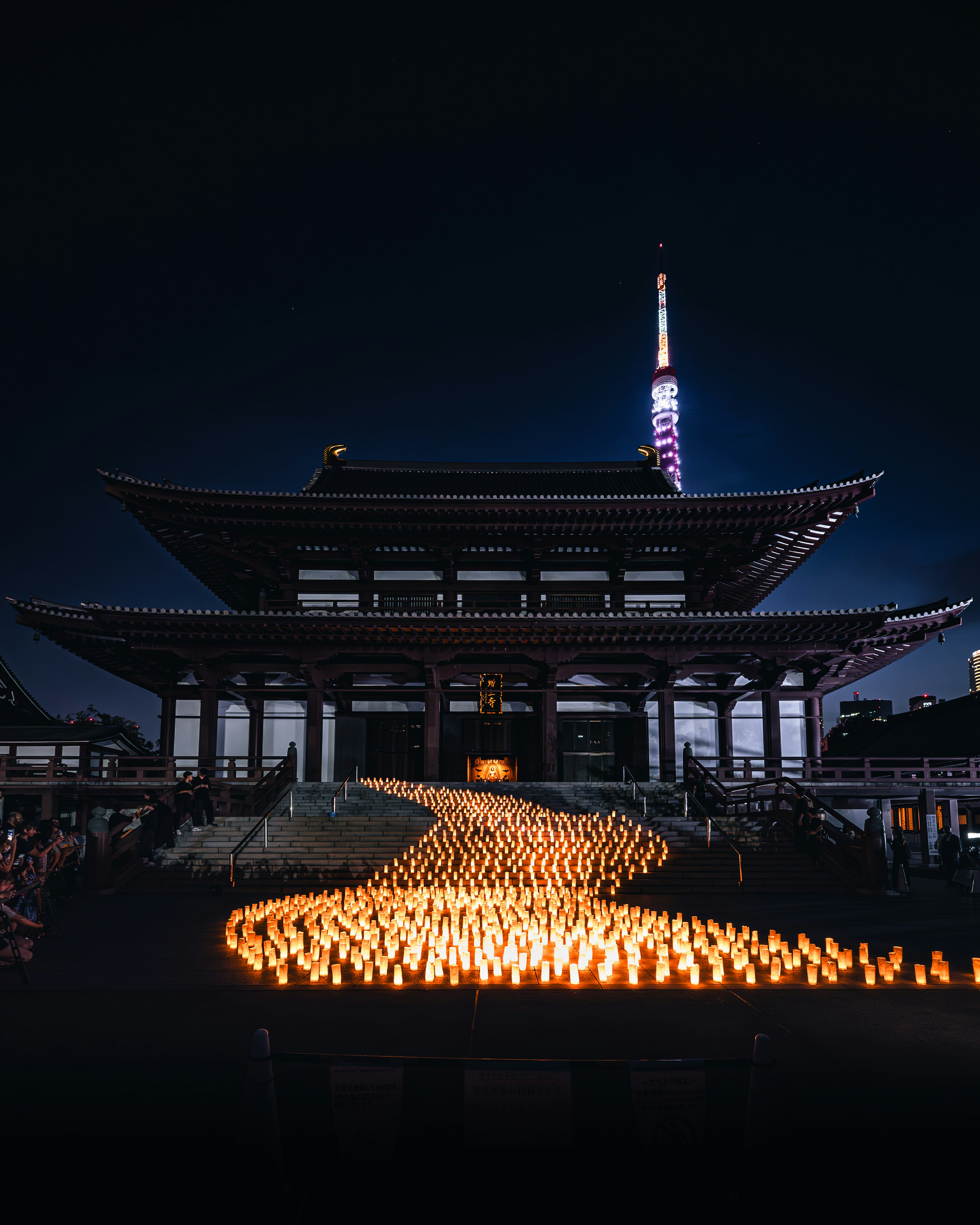 Scena notturna con candele davanti a un tempio e alla Torre di Tokyo