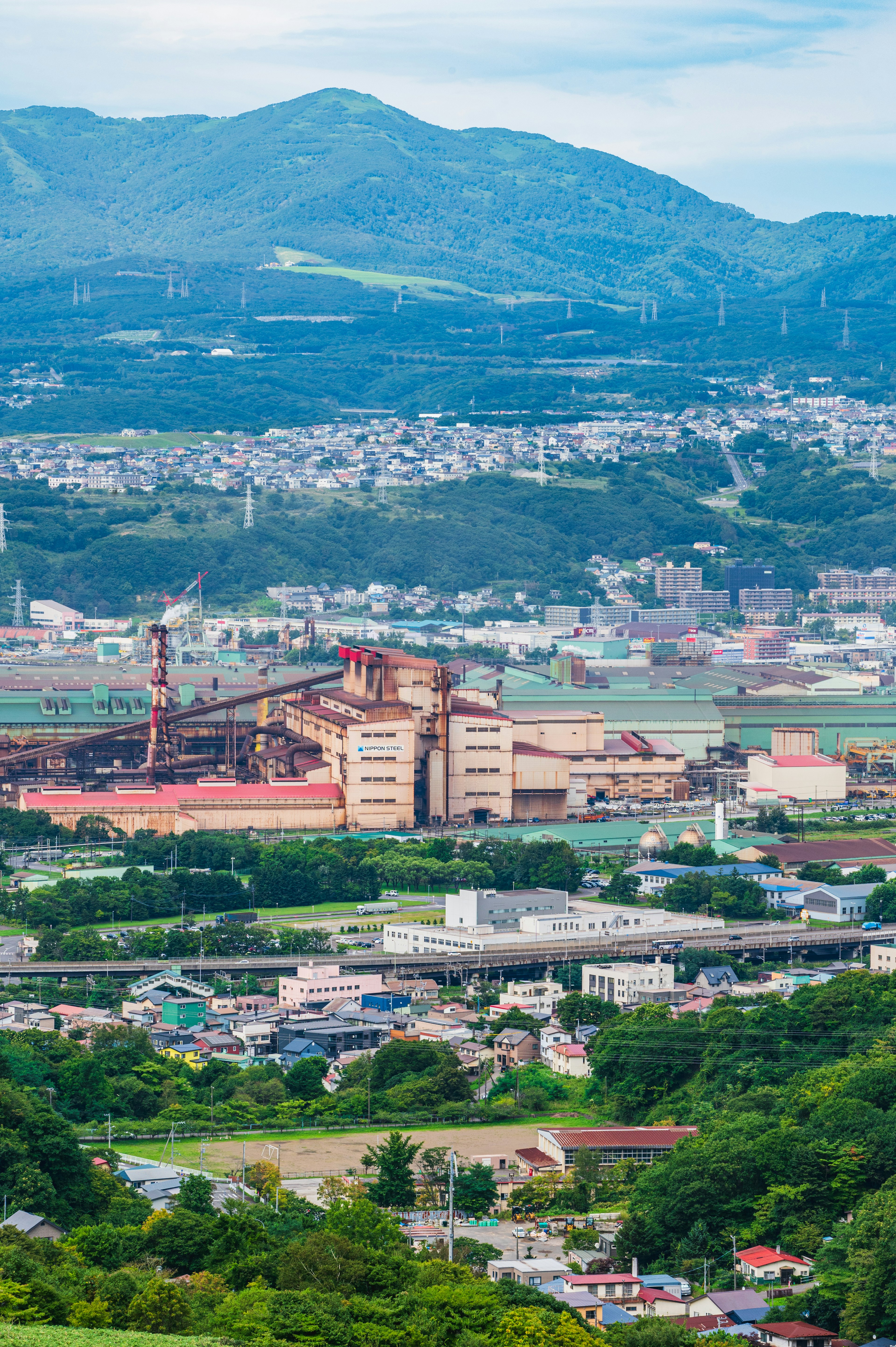 山々に囲まれた工業地域の風景 大きな工場とその周辺の住宅地