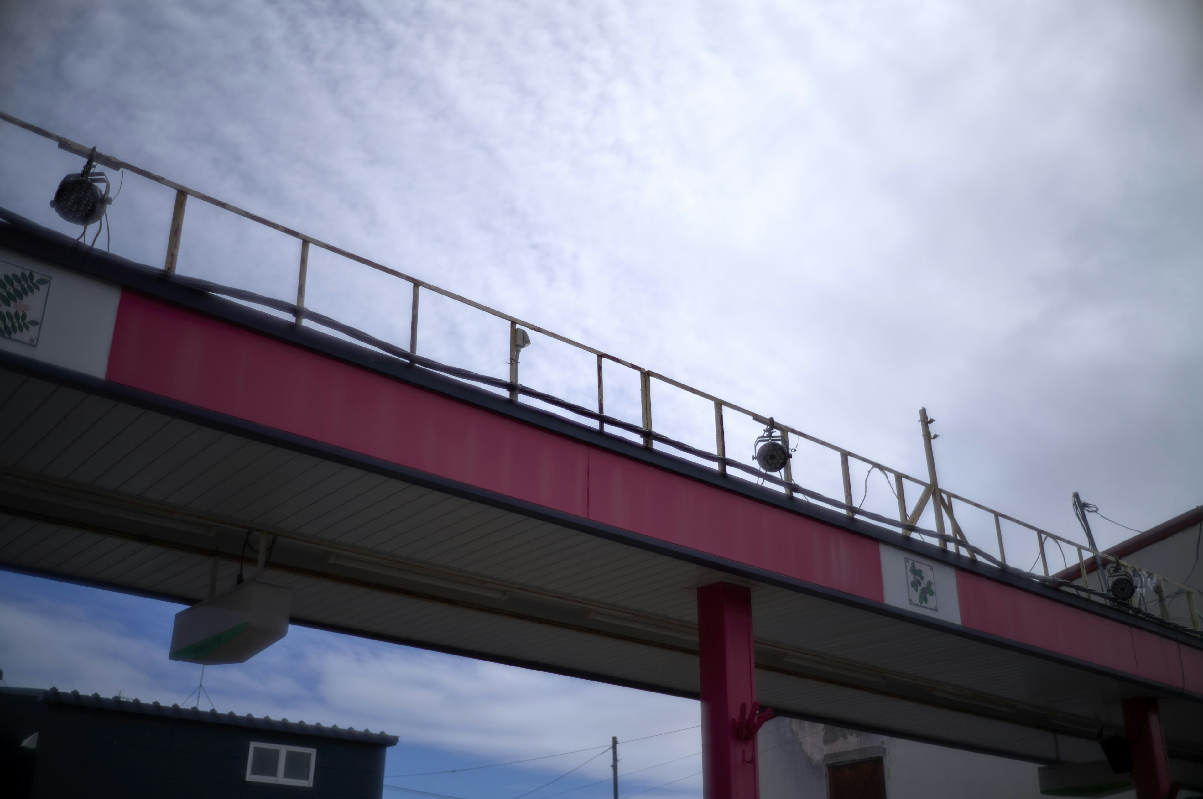 Erhöhter Fußgängerbrücke mit roten Säulen und bewölktem Himmel