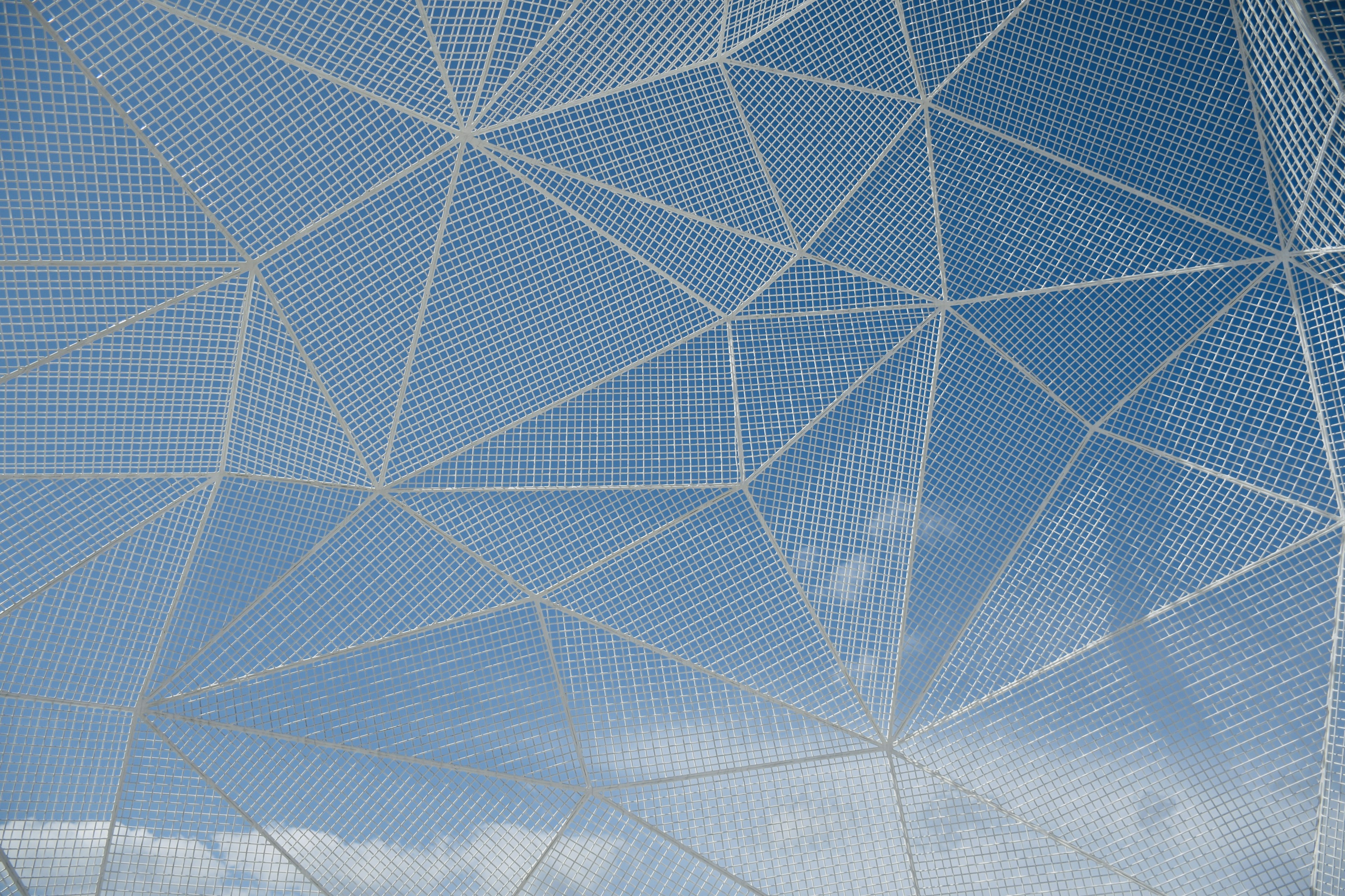 White mesh structure against a blue sky with clouds