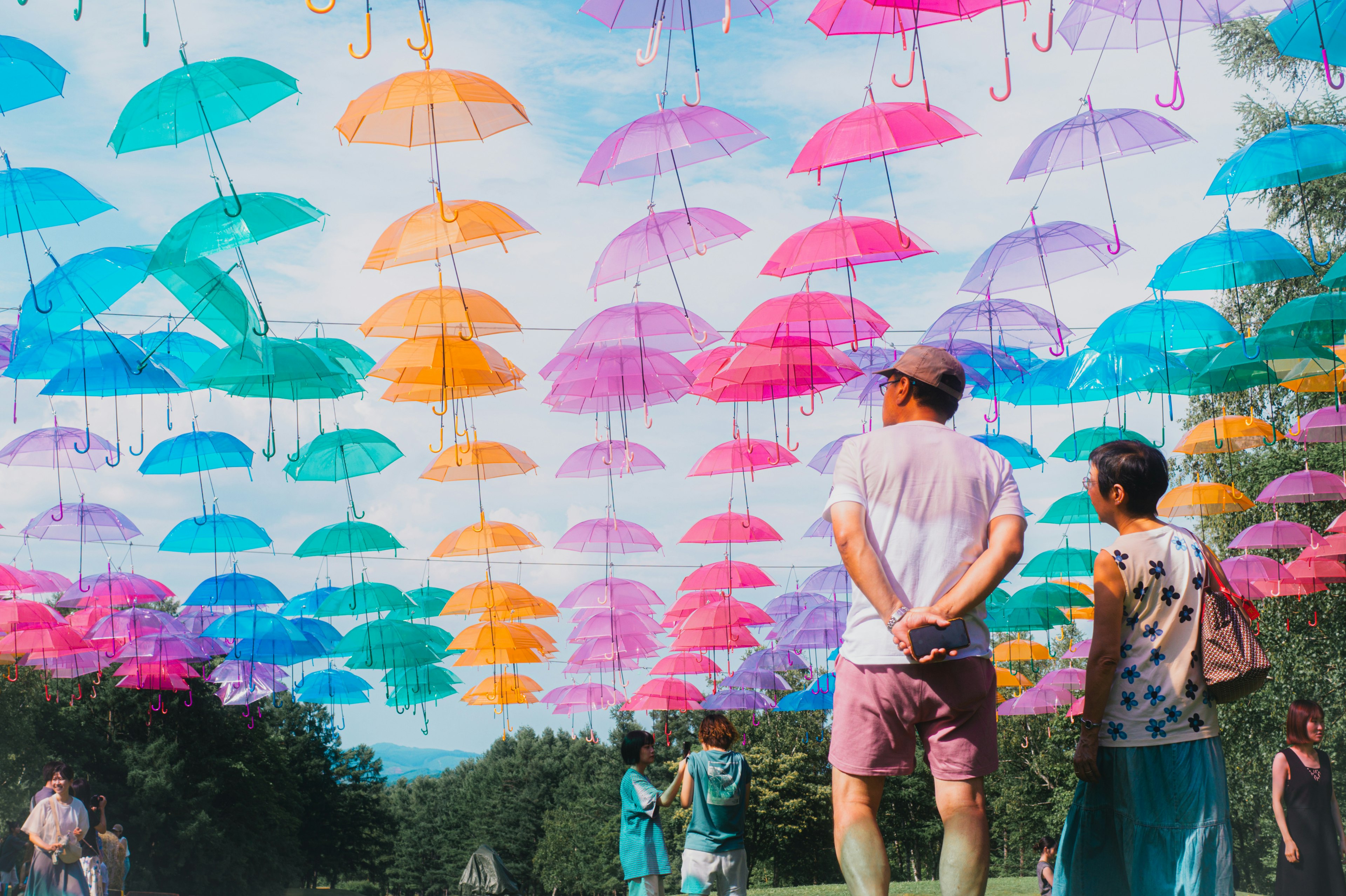 People looking up at colorful umbrellas suspended in the sky