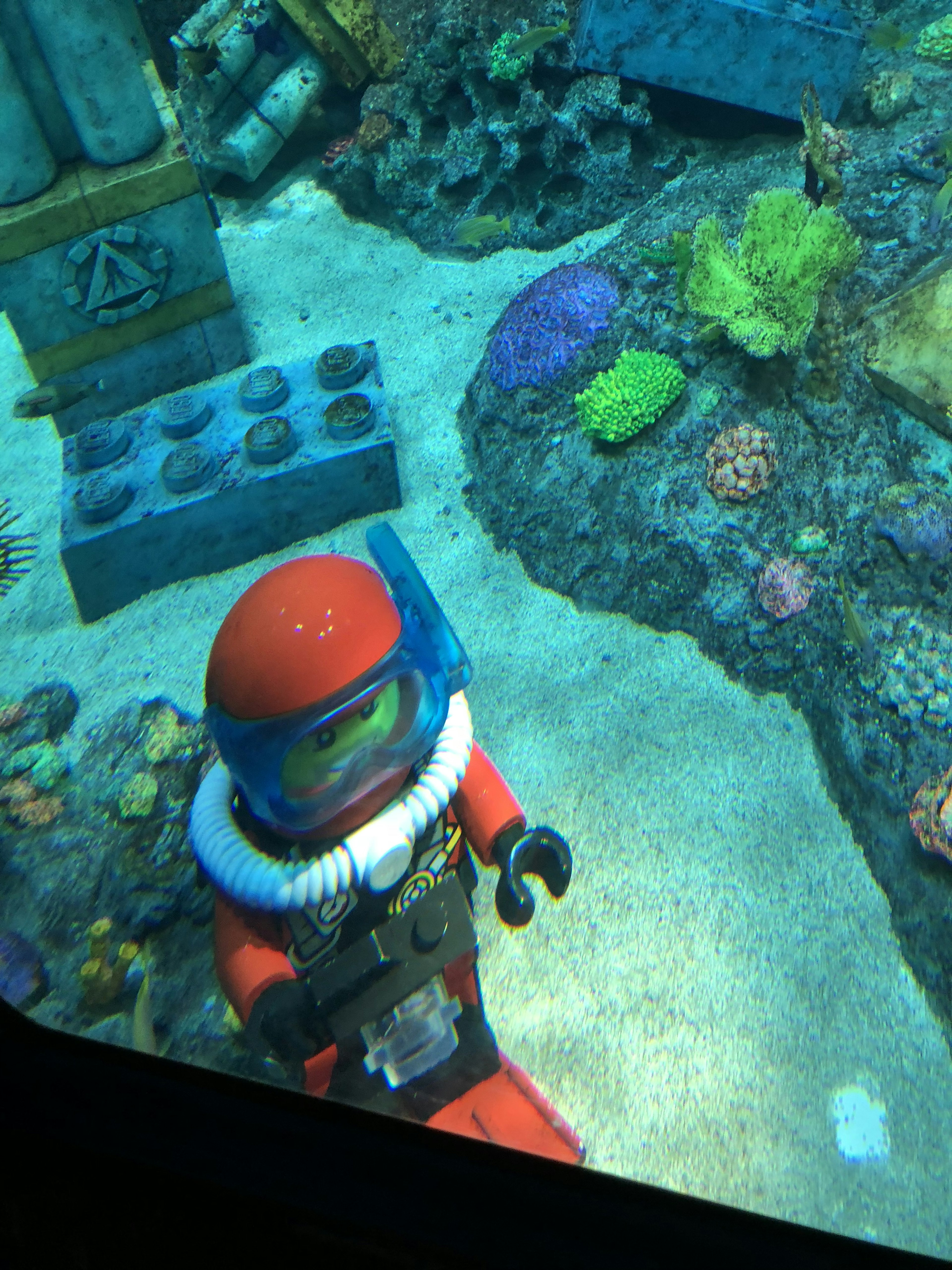 A LEGO diver swimming among colorful corals underwater