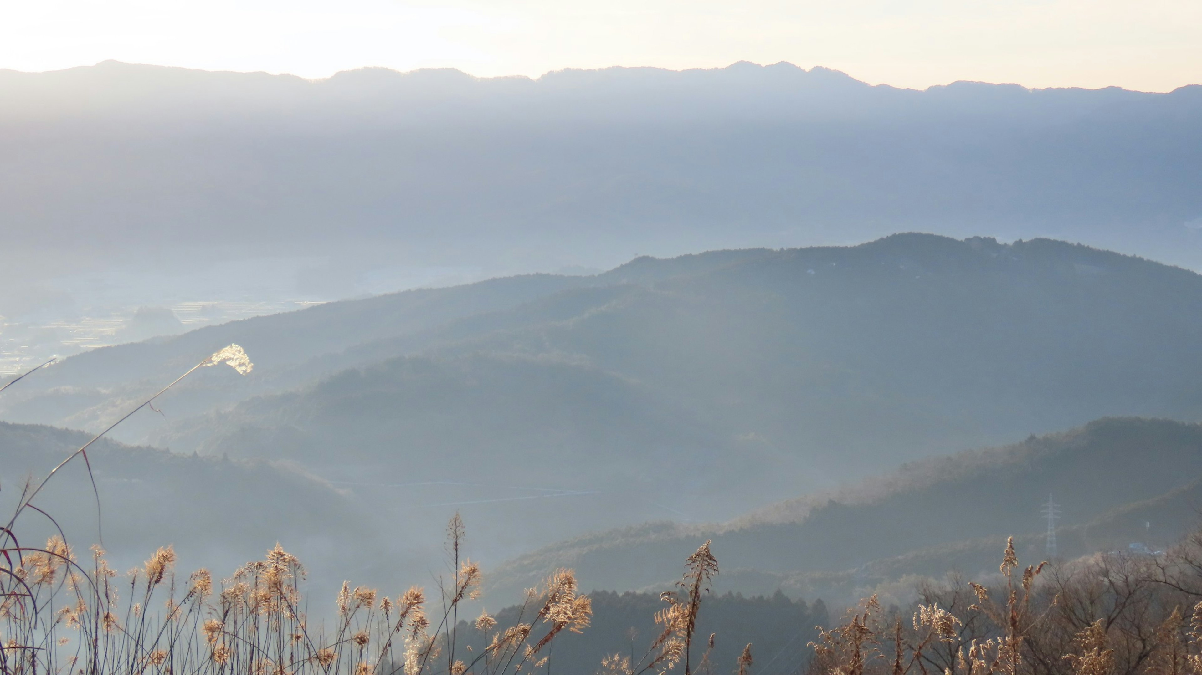 霧に包まれた山々と柔らかな光が差し込む風景