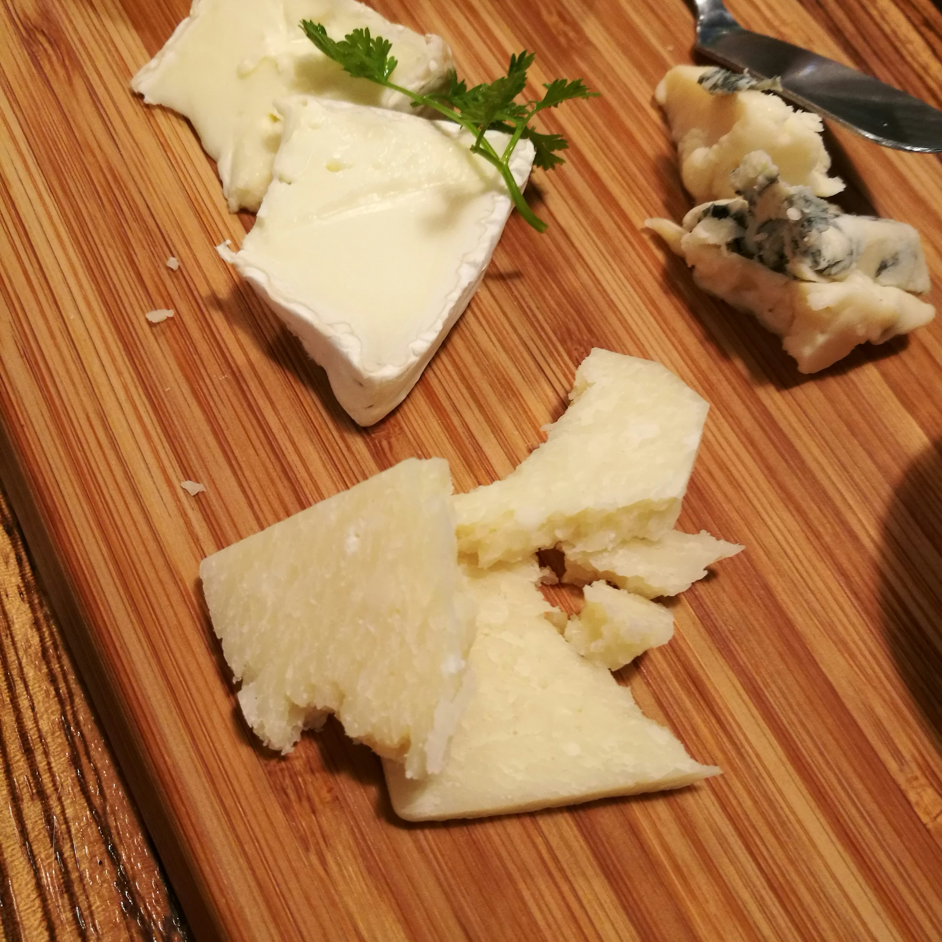 Various types of cheese and herbs on a wooden board