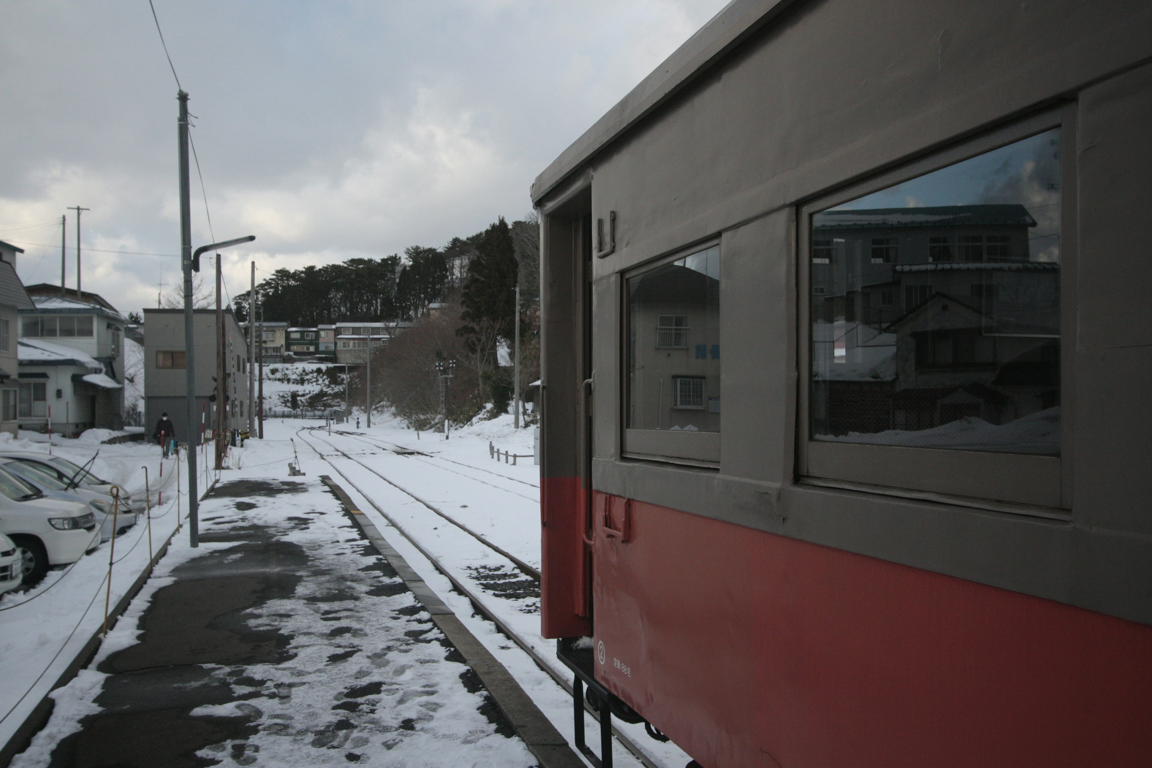 Red train parked next to snow-covered tracks