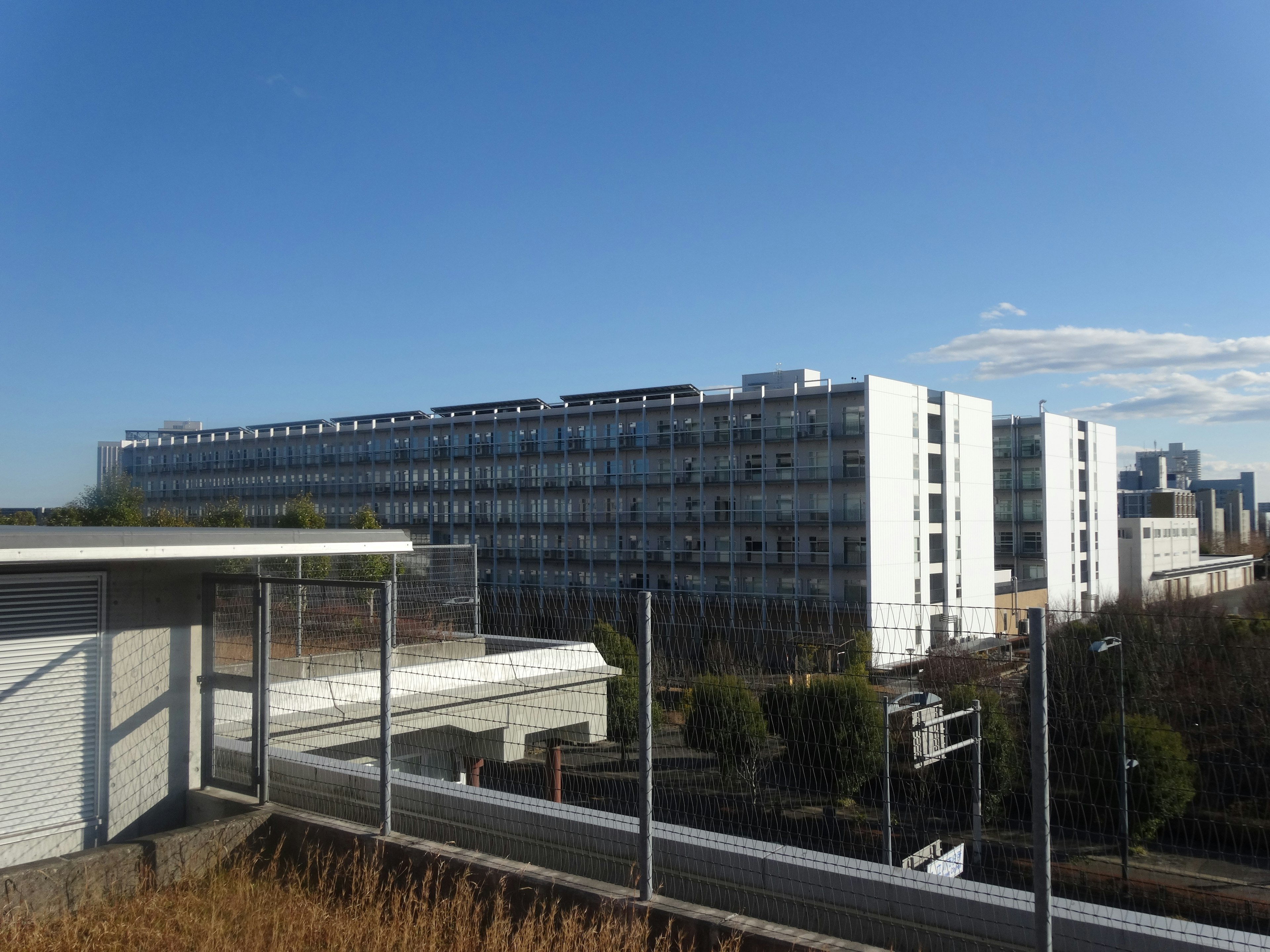 青空の下にある現代的な建物の外観と近くの低層建物