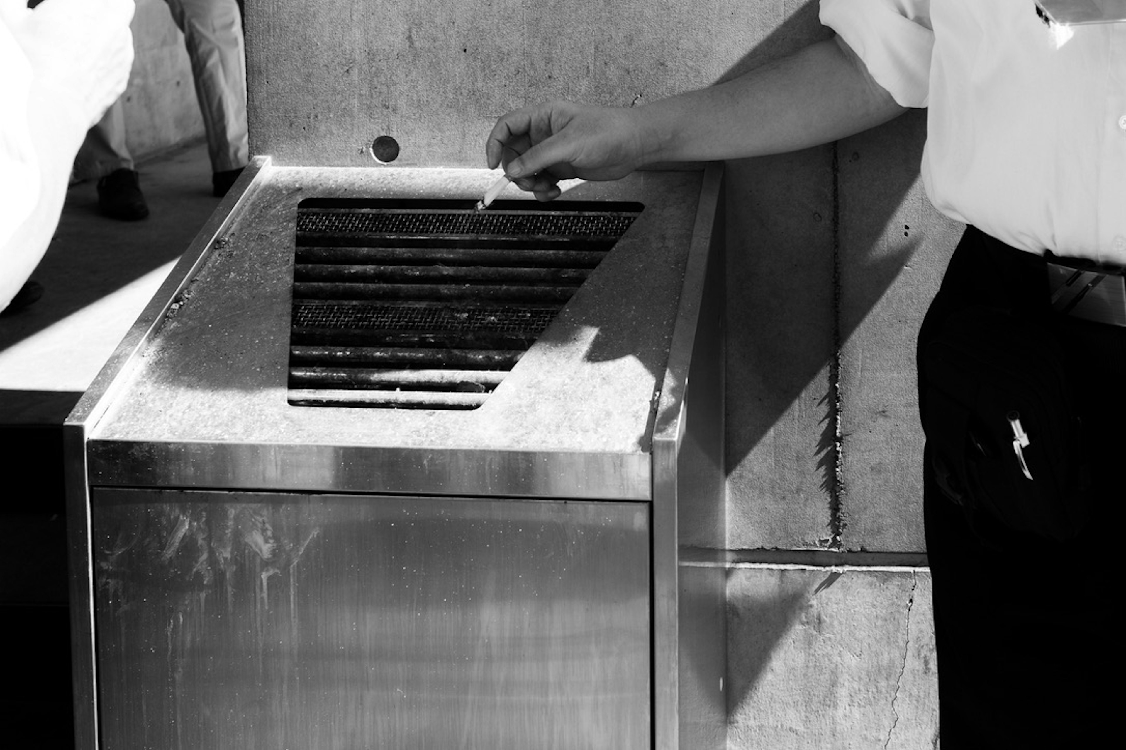 Person in a white shirt reaching for a steel grill