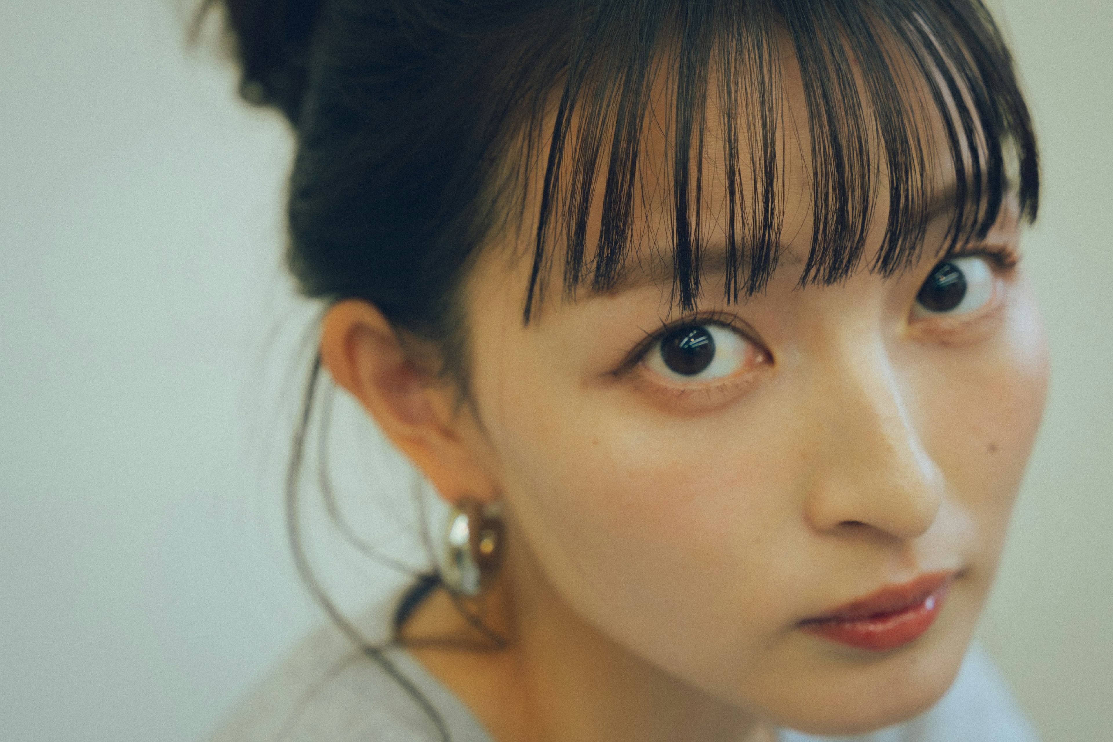 Retrato de una mujer con peinado de moño sonrisa suave ojos grandes y maquillaje natural