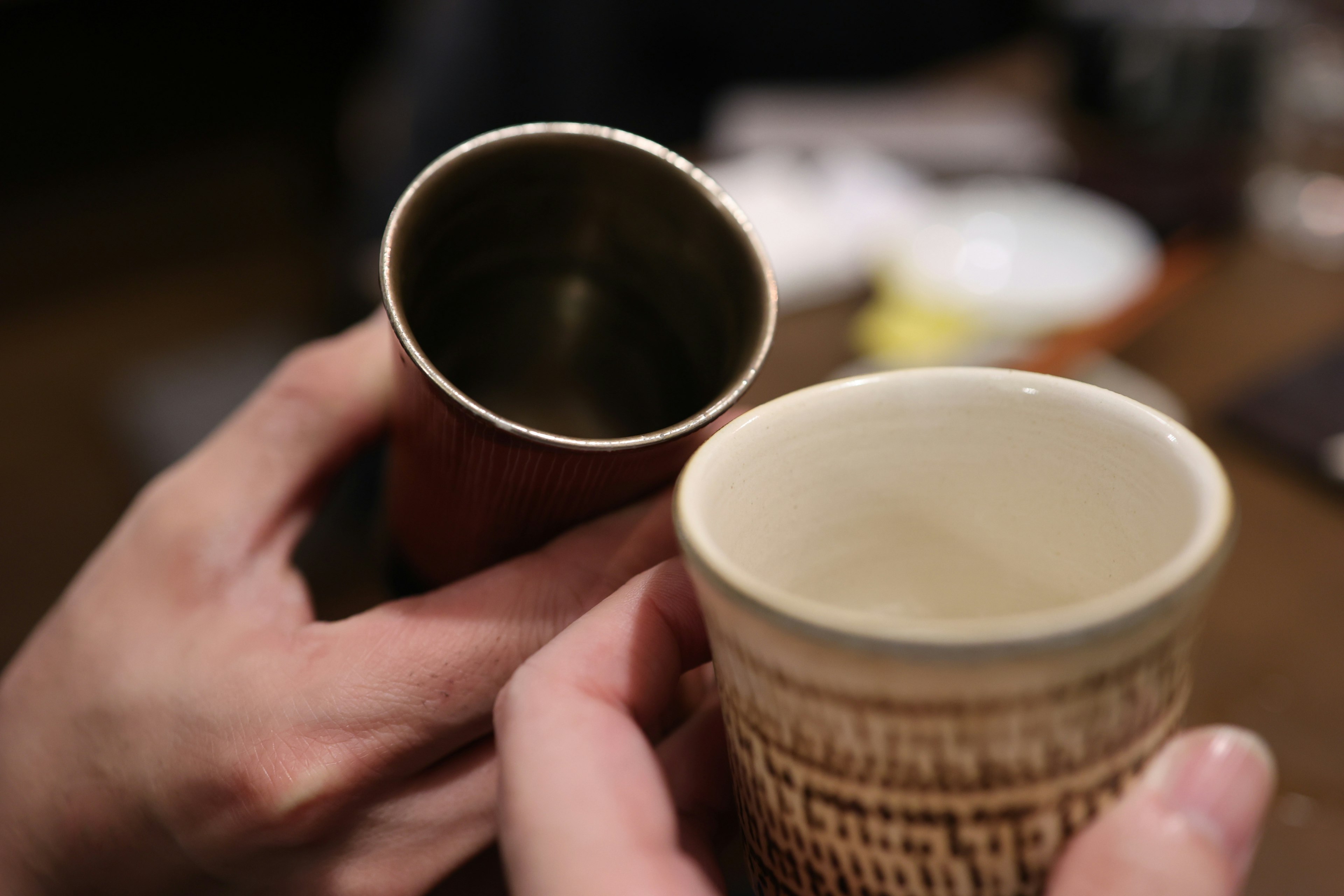 Close-up shot of two different cups held in hands