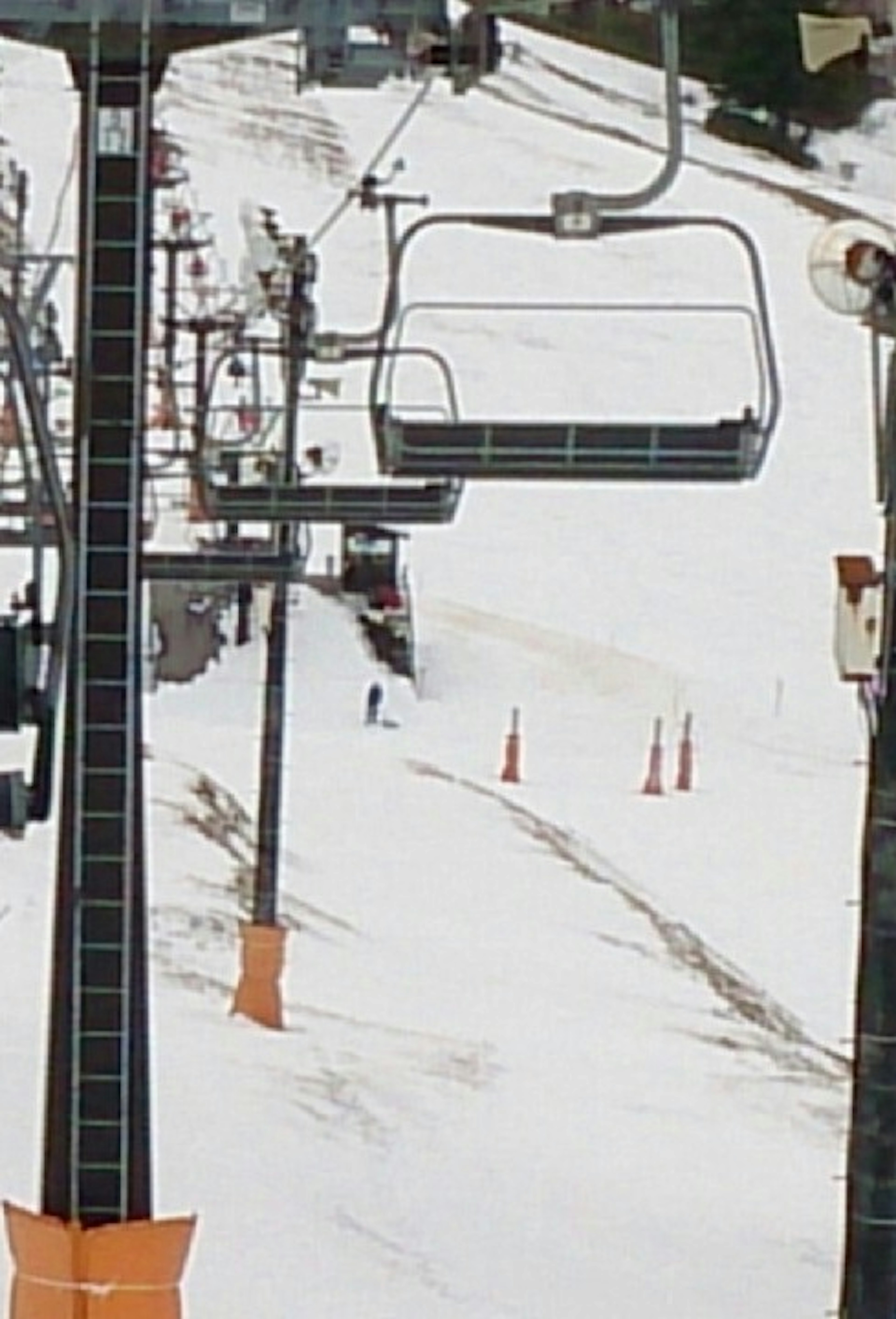 Snow-covered ski resort scene featuring a ski lift and traffic cones