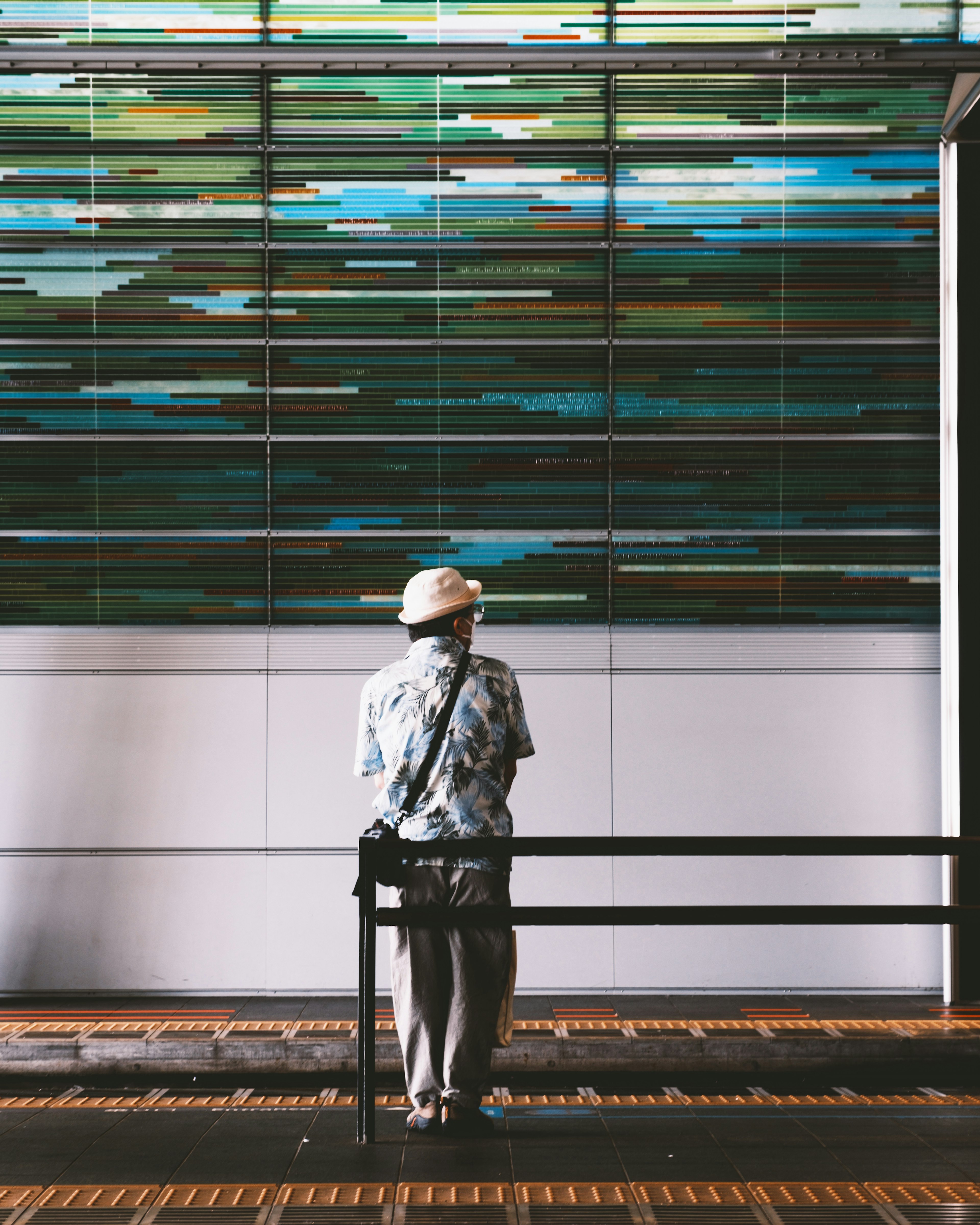 Un homme âgé se tient près d'un banc en regardant une fresque colorée