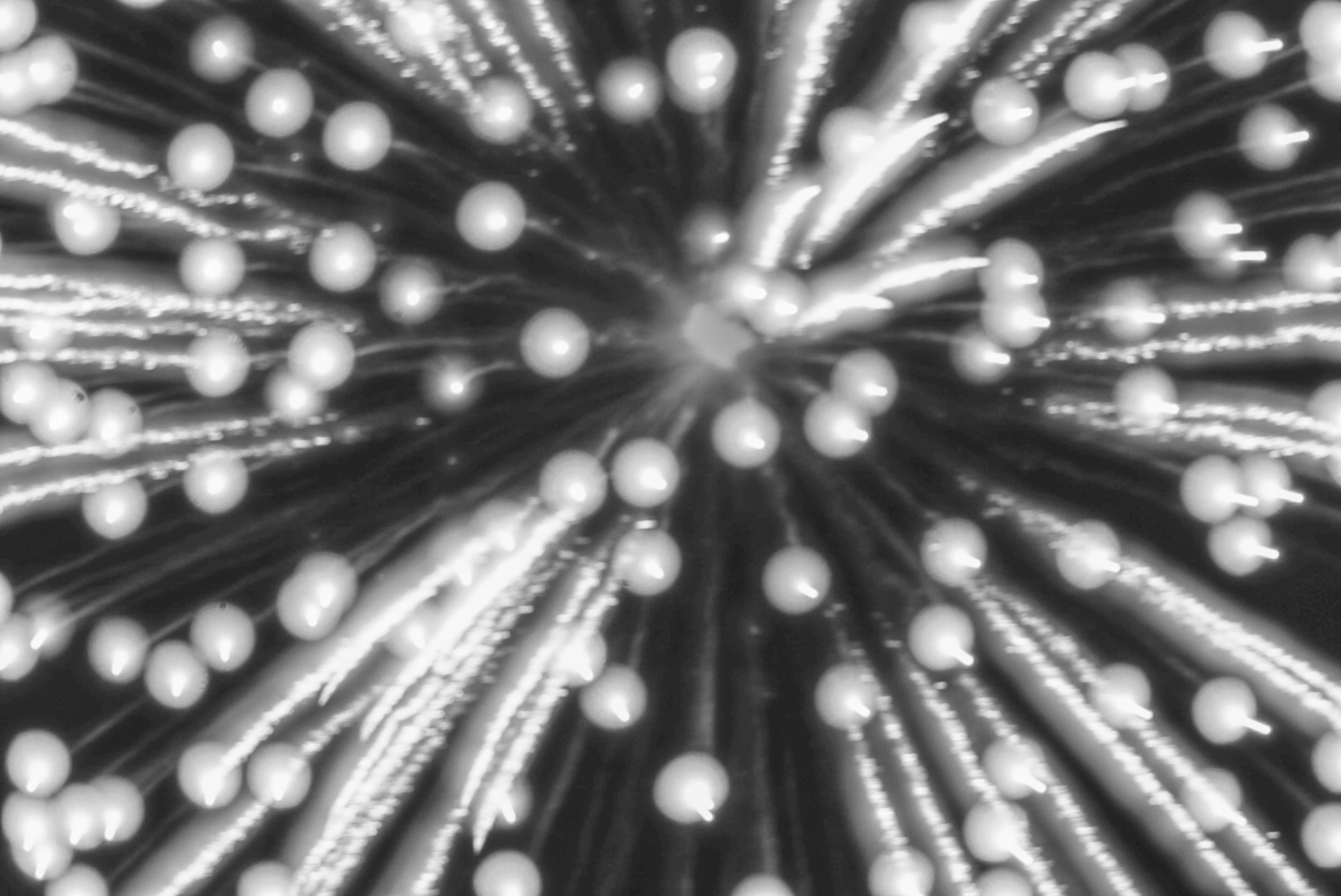 Black and white image of fireworks-like light trails radiating outward