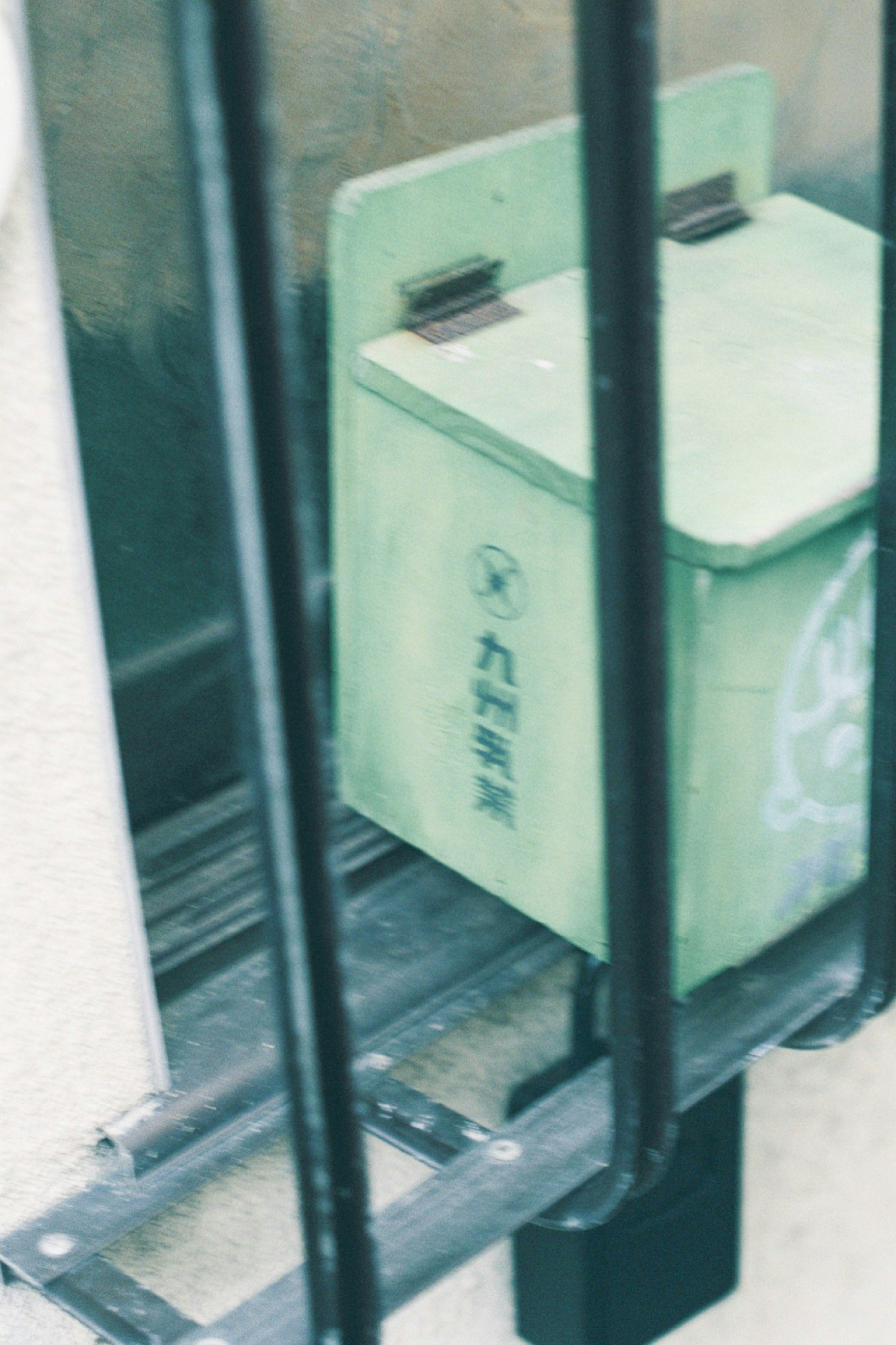 A green mailbox placed behind a grid