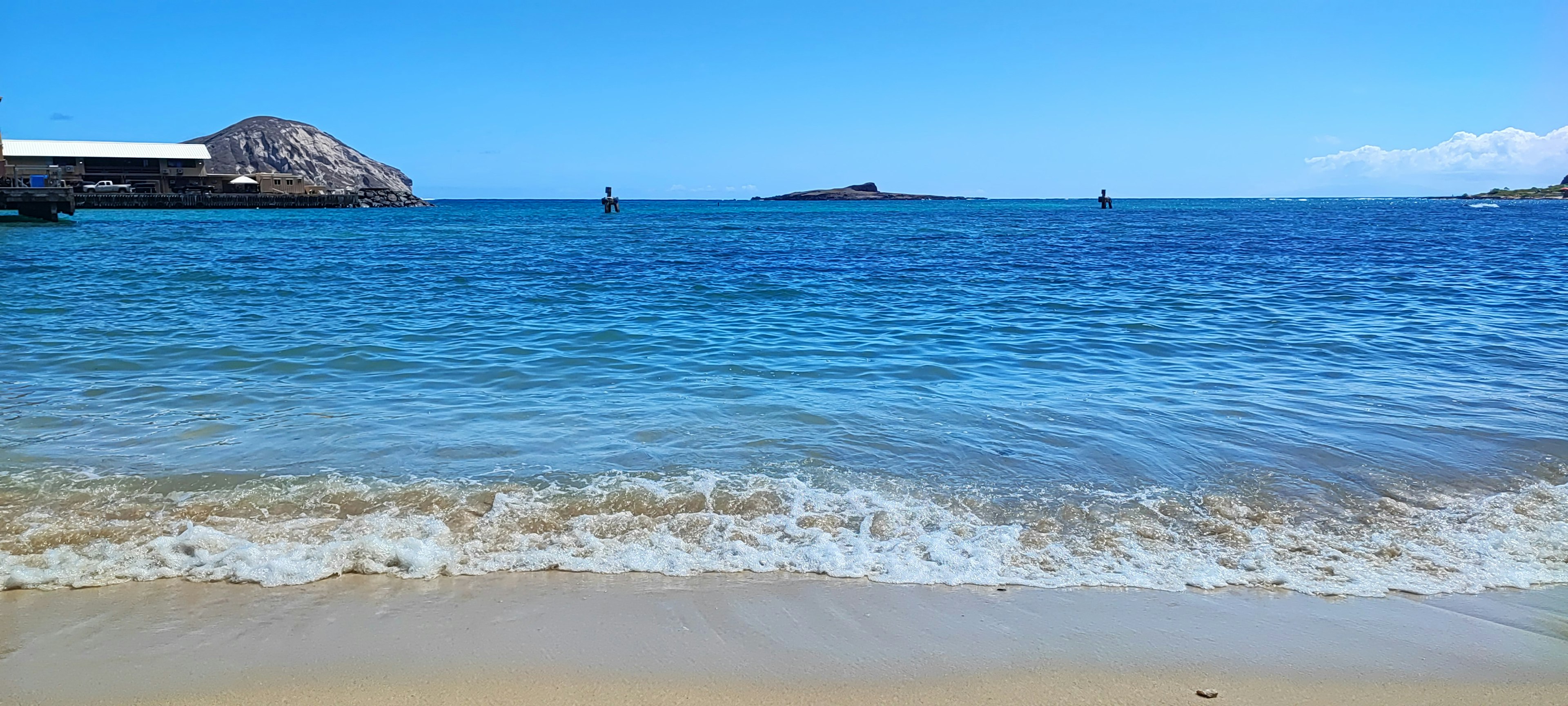 ทิวทัศน์สวยงามของทะเลสีฟ้าและชายหาดทราย เรือที่ลอยอยู่บนผิวน้ำสงบ