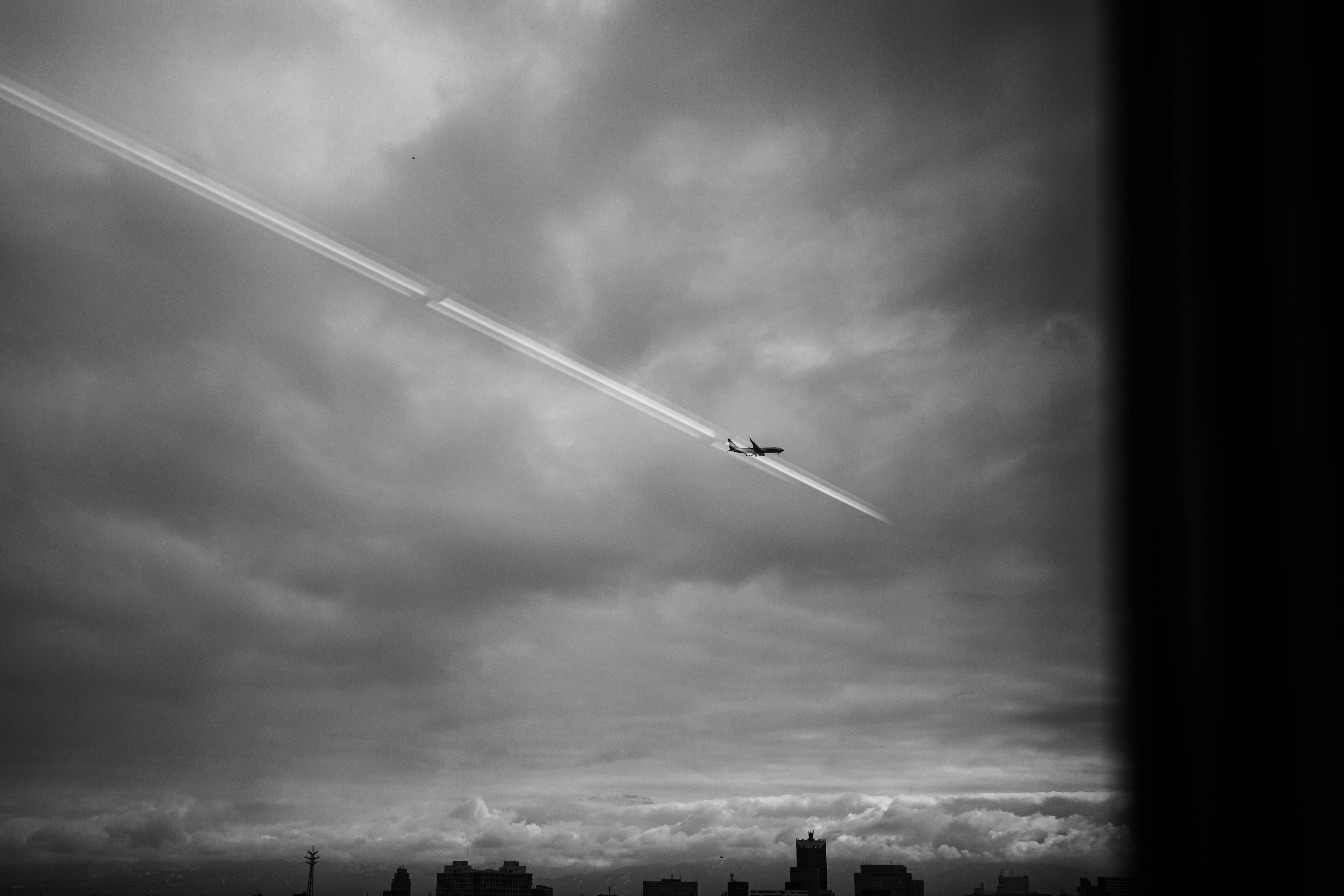 雲の中を飛ぶ飛行機とその航跡