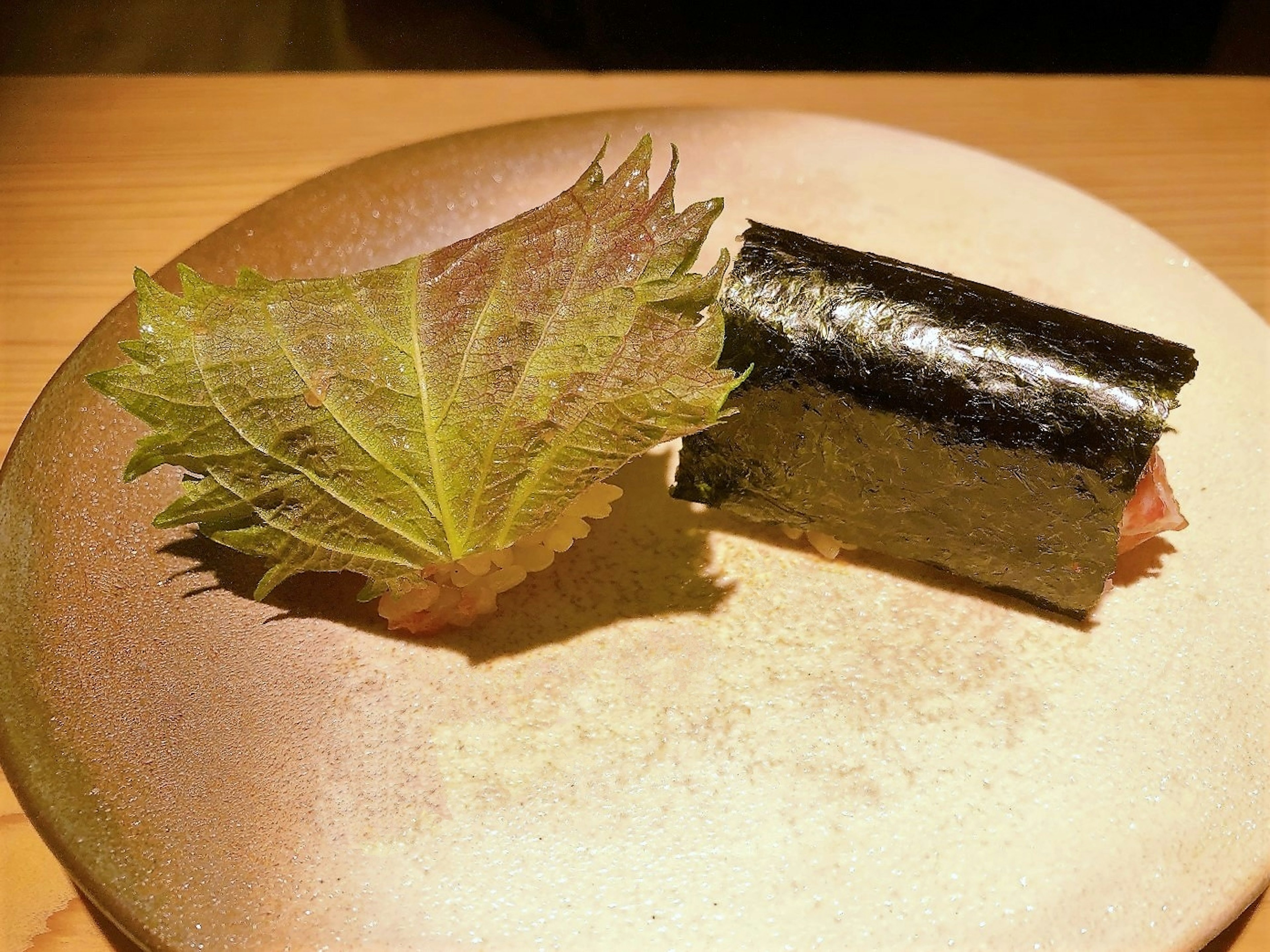 皿の上にある海苔巻きと大葉の葉