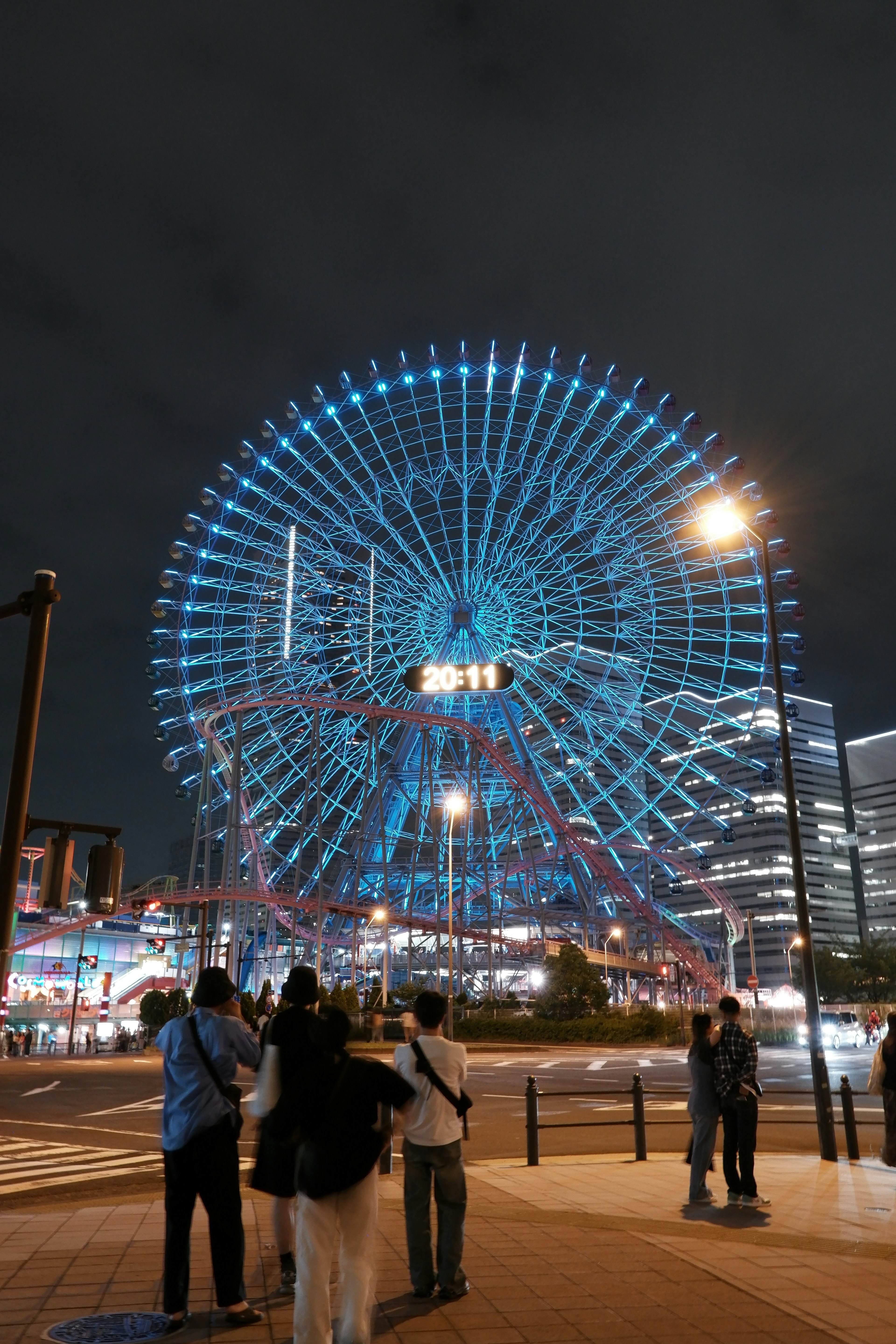 夜間大型摩天輪的亮燈景觀，前景有行人