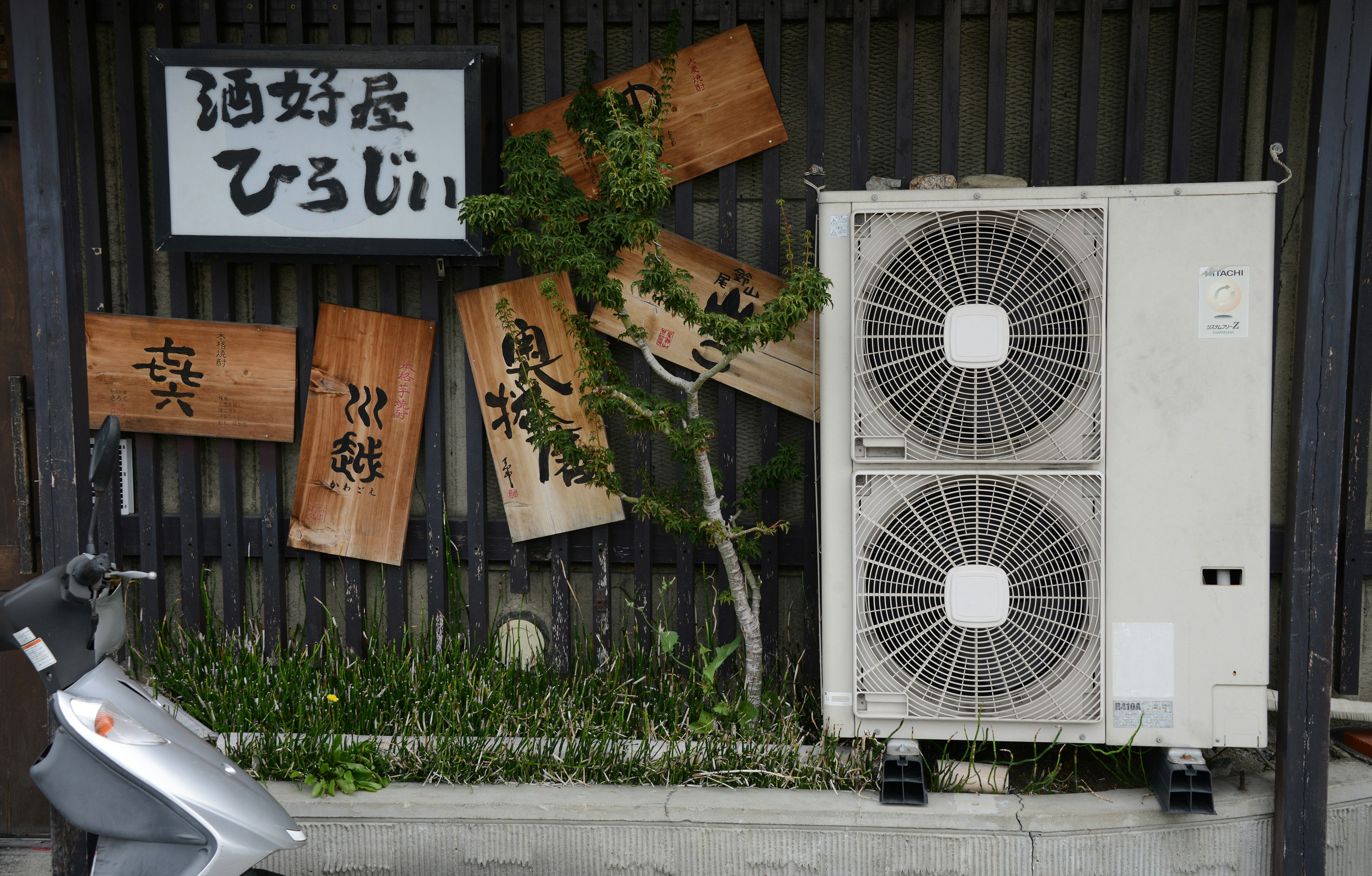 Escena callejera japonesa con letreros de madera y una unidad de aire acondicionado