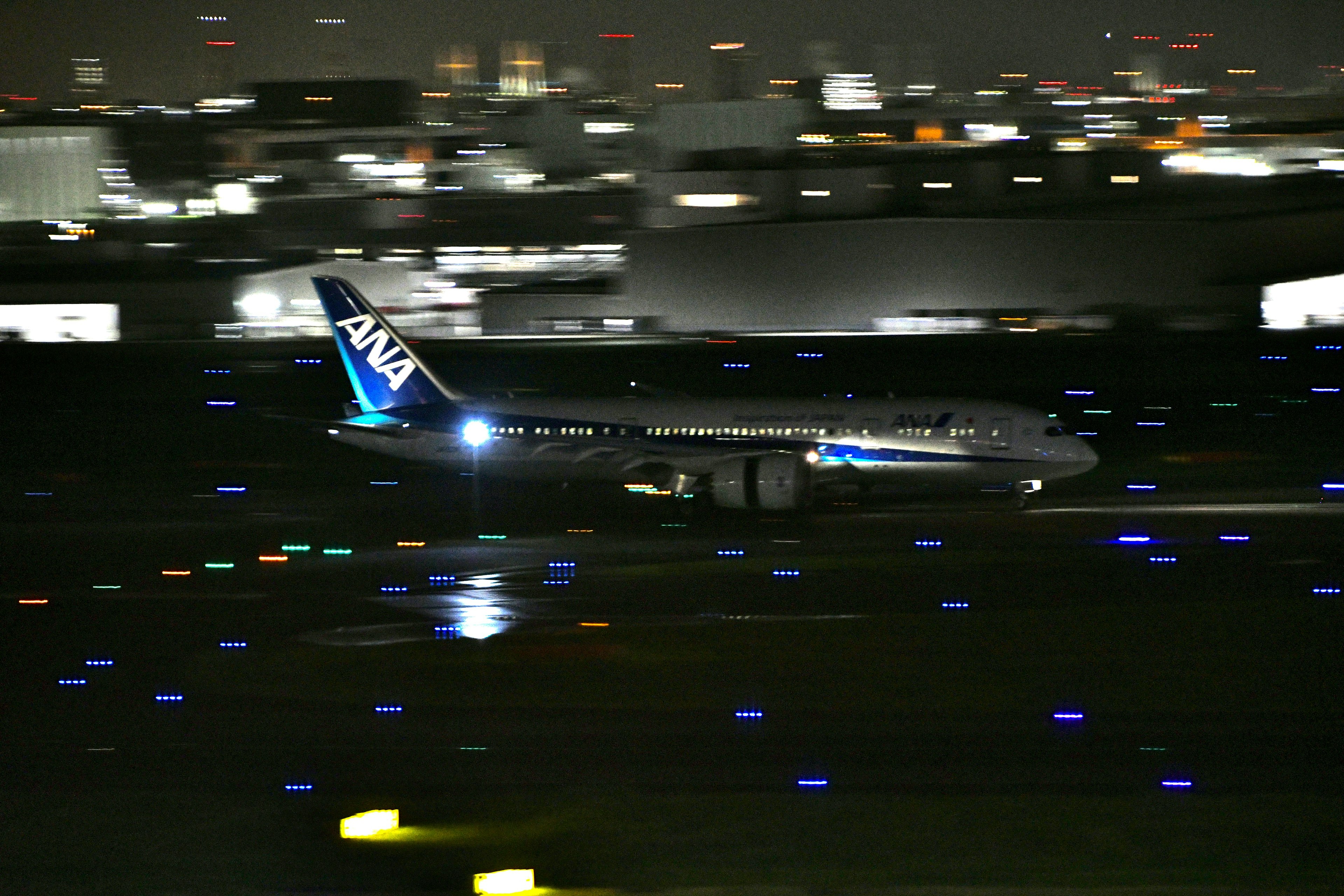 夜の空港で着陸するANAの航空機