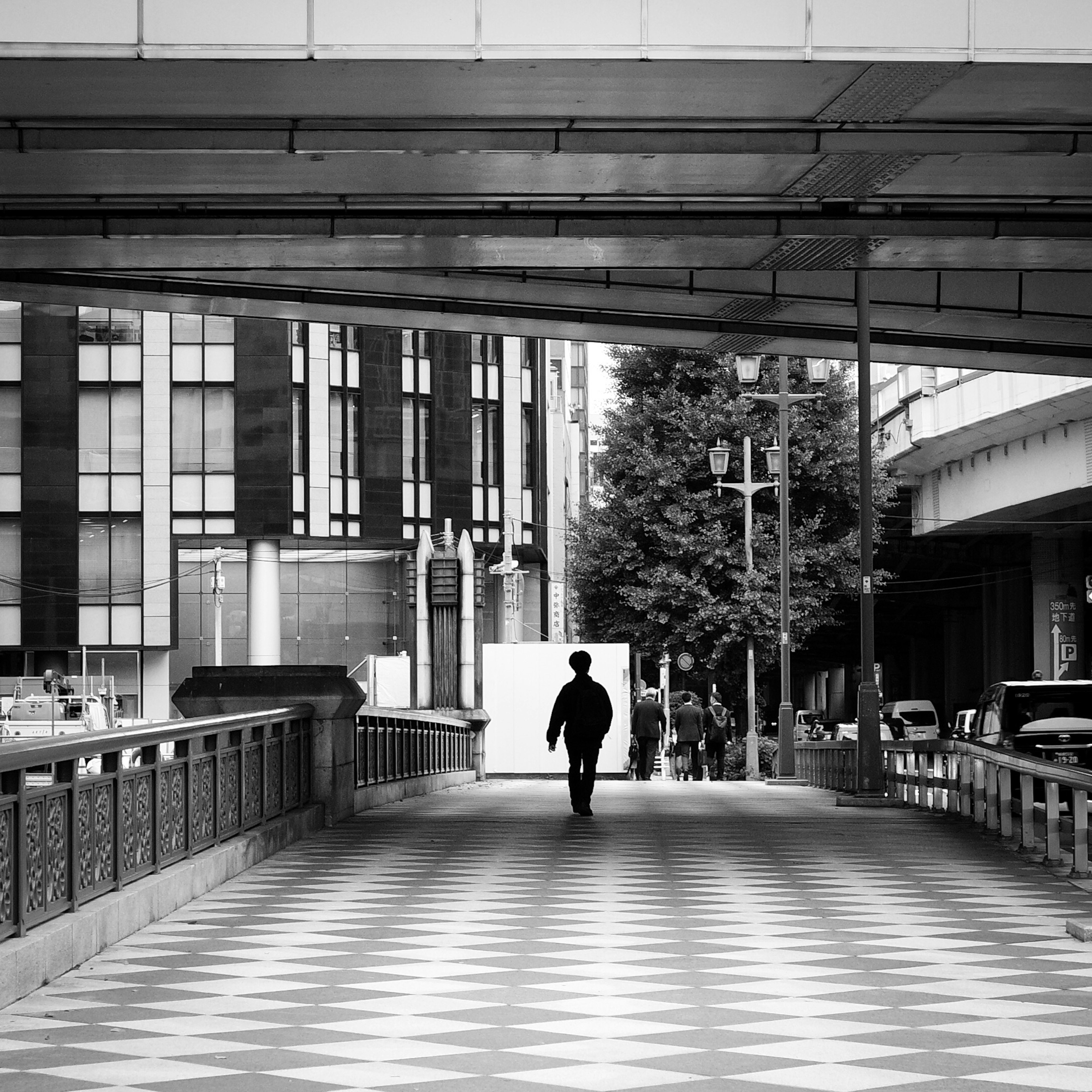 Silhouette of a person walking in a black and white urban scene with geometric patterned floor