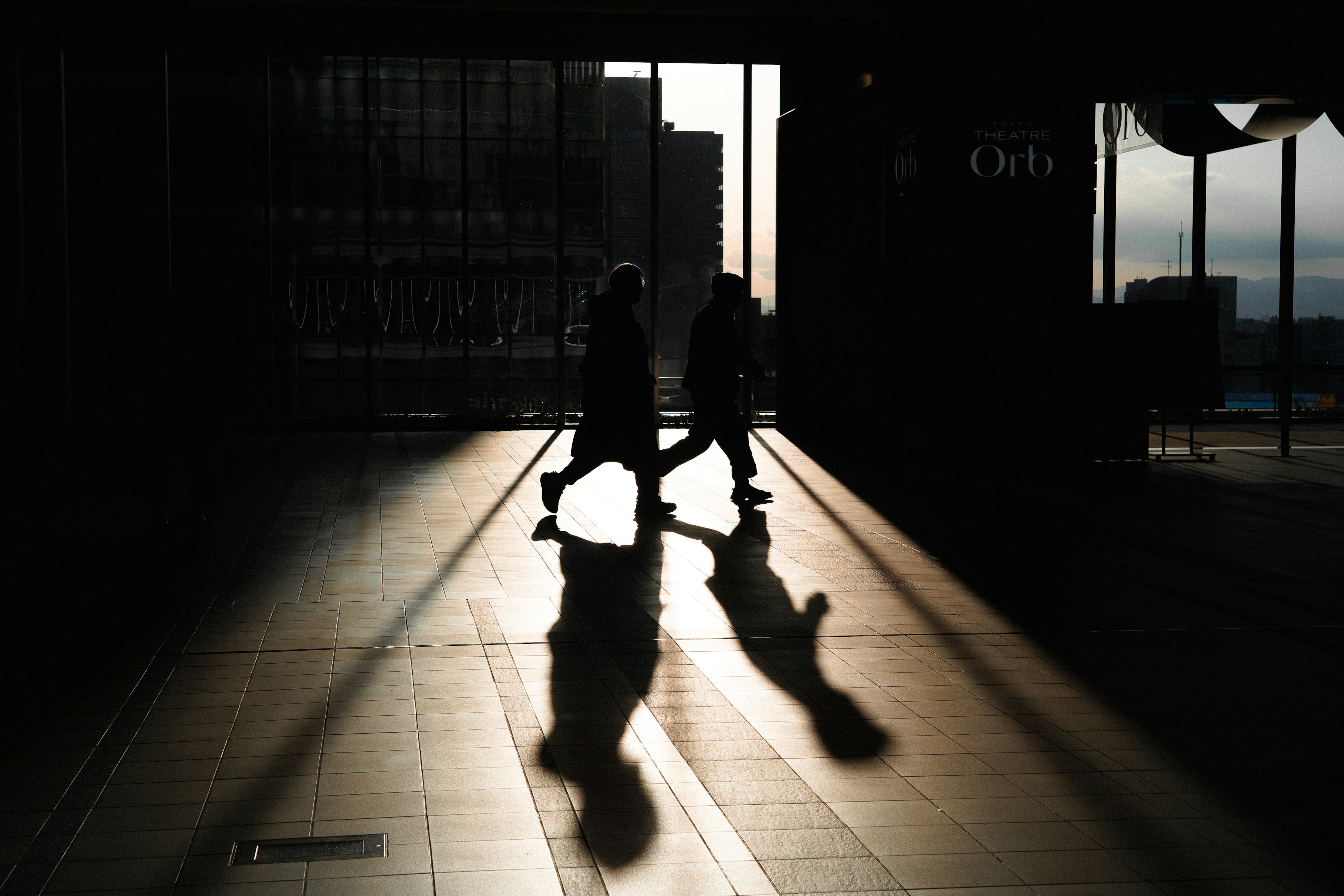 Silueta de dos personas caminando en la sombra con largas sombras en el suelo