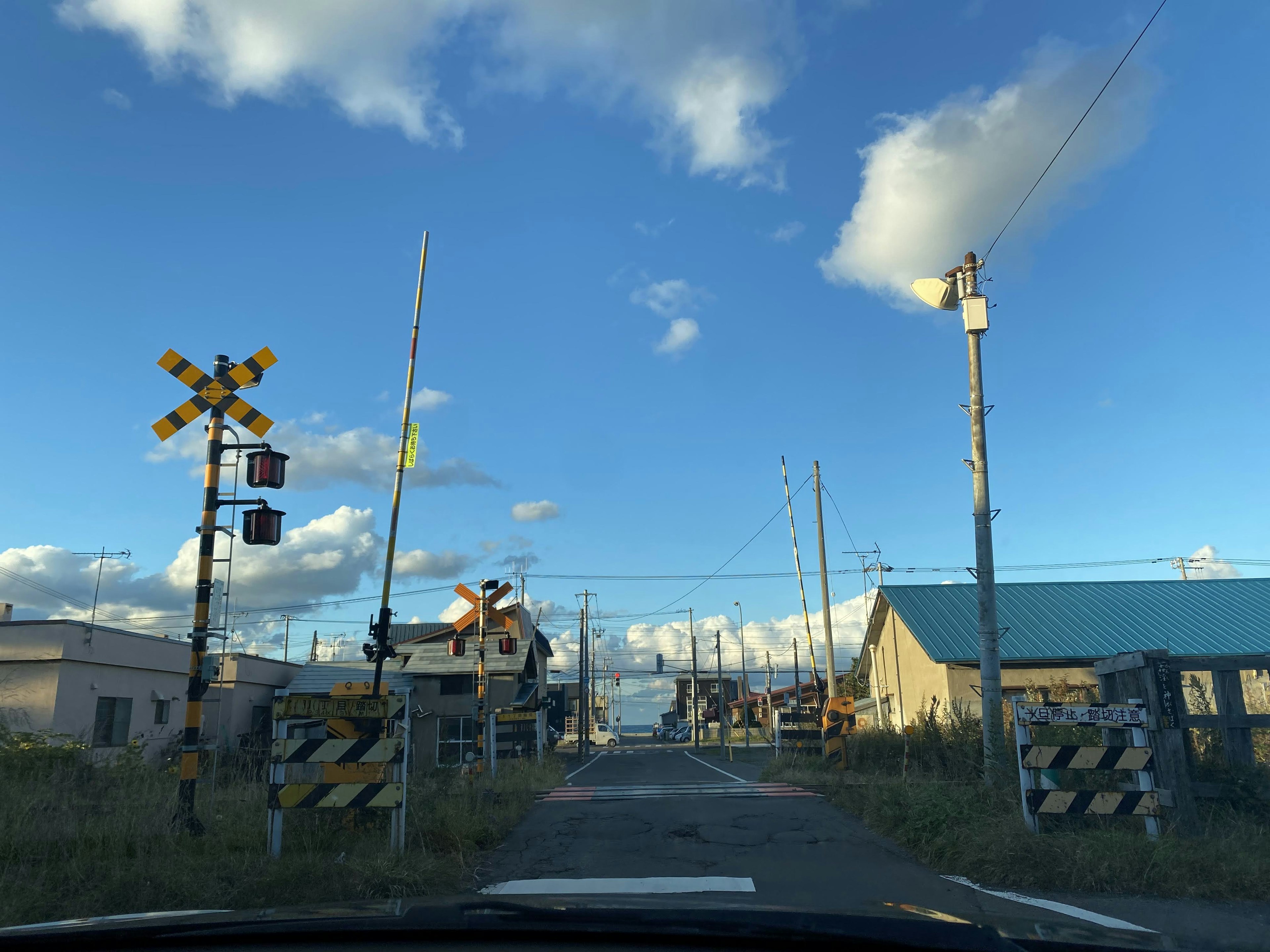 Railroad crossing under a blue sky with surrounding buildings