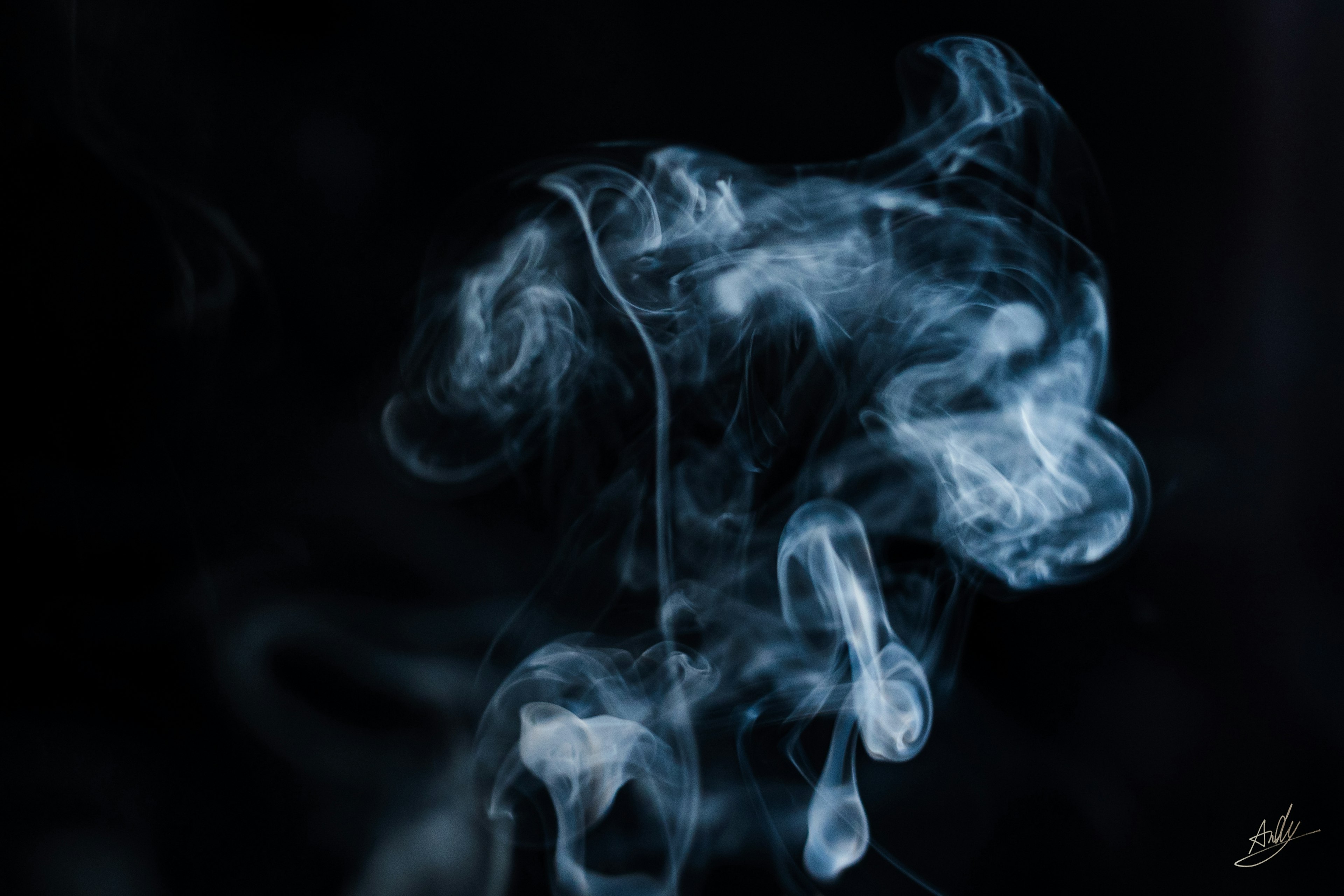 Hermosos patrones de humo azul que flotan sobre un fondo negro