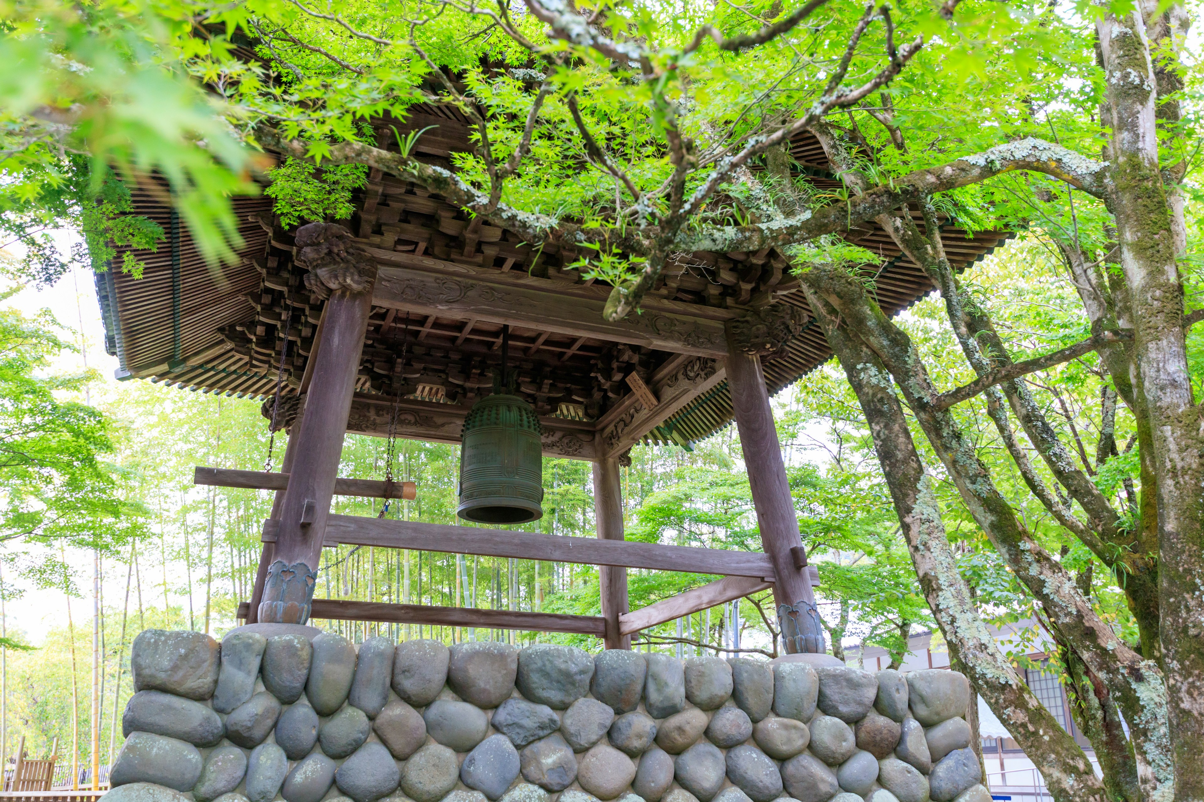 Traditional bell tower surrounded by green leaves and stone base